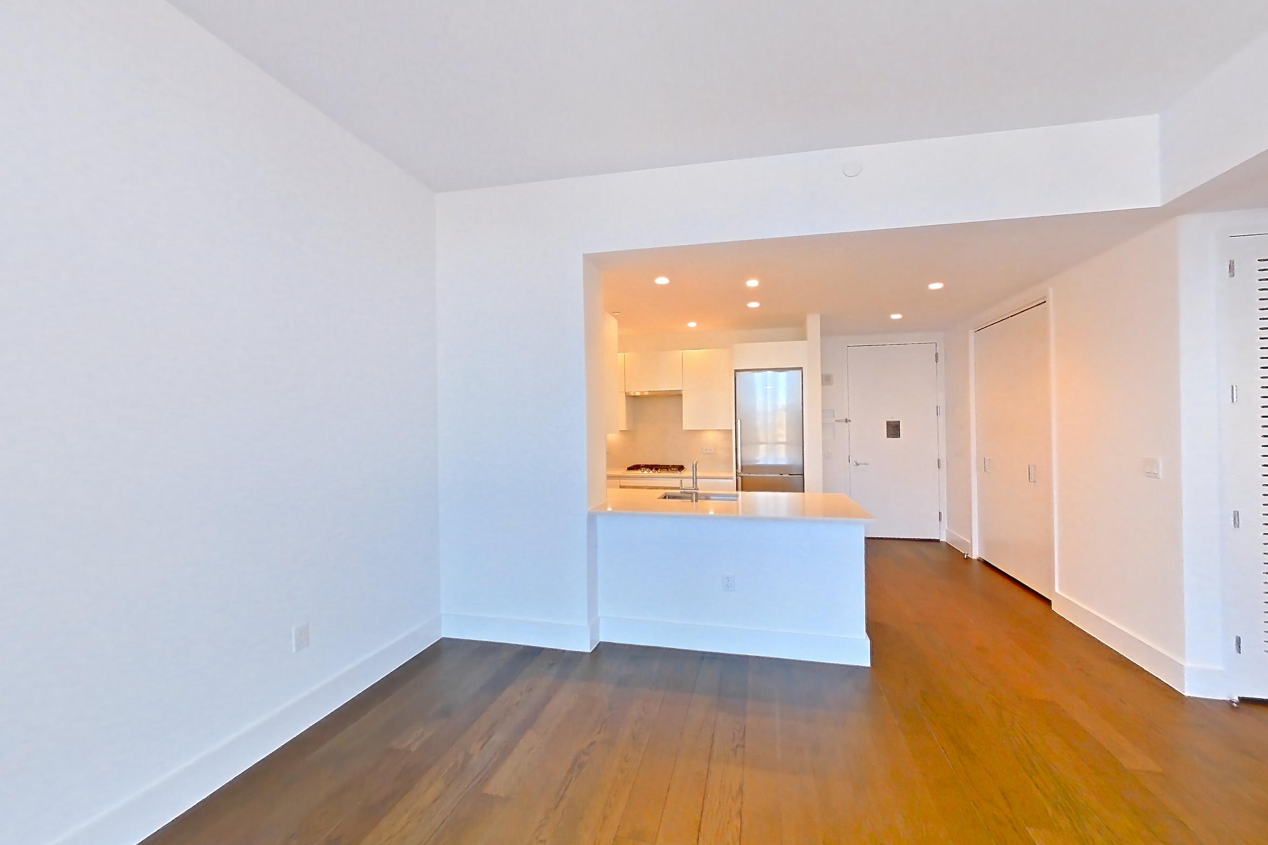 Living room with dark wood-finish flooring, refrigerator, stainless steel appliances, and wood-finish flooring, Apartment 33k at Summit NYC
