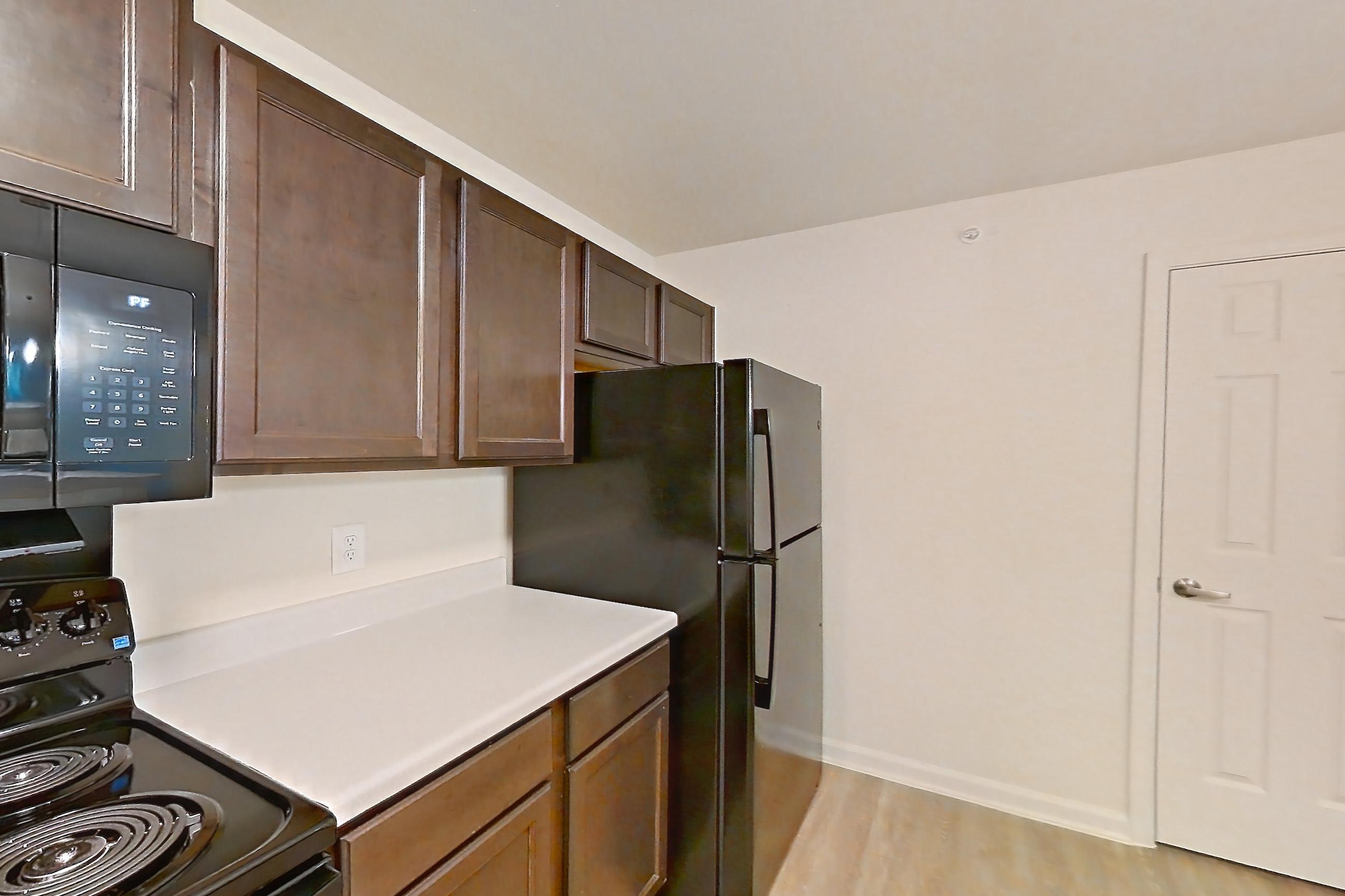 Kitchen with black appliances, dishwasher, electric range, light countertops, light wood-finish flooring, oven/range, and refrigerator, Apartment 3002 at Ivy Ridge