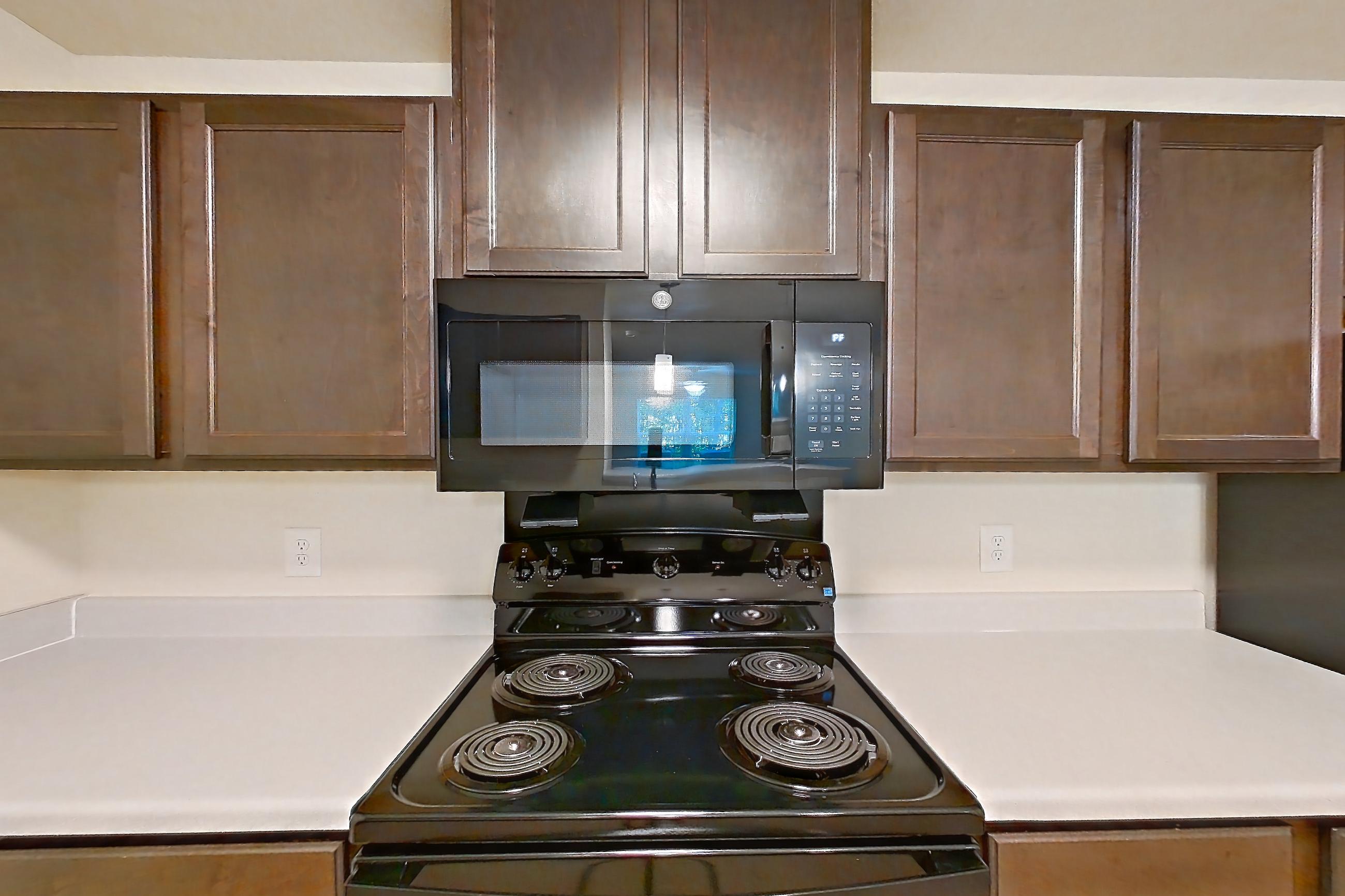 Kitchen with black appliances, dishwasher, electric range, light countertops, light wood-finish flooring, oven/range, and refrigerator, Apartment 3002 at Ivy Ridge