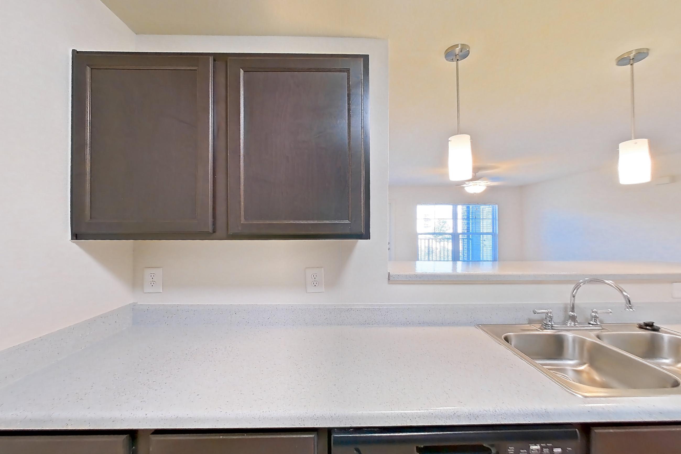 Kitchen with black appliances, dishwasher, electric range, light countertops, light stone countertops, light wood-finish flooring, microwave, oven/range, and refrigerator, Apartment 7206 at Ivy Ridge