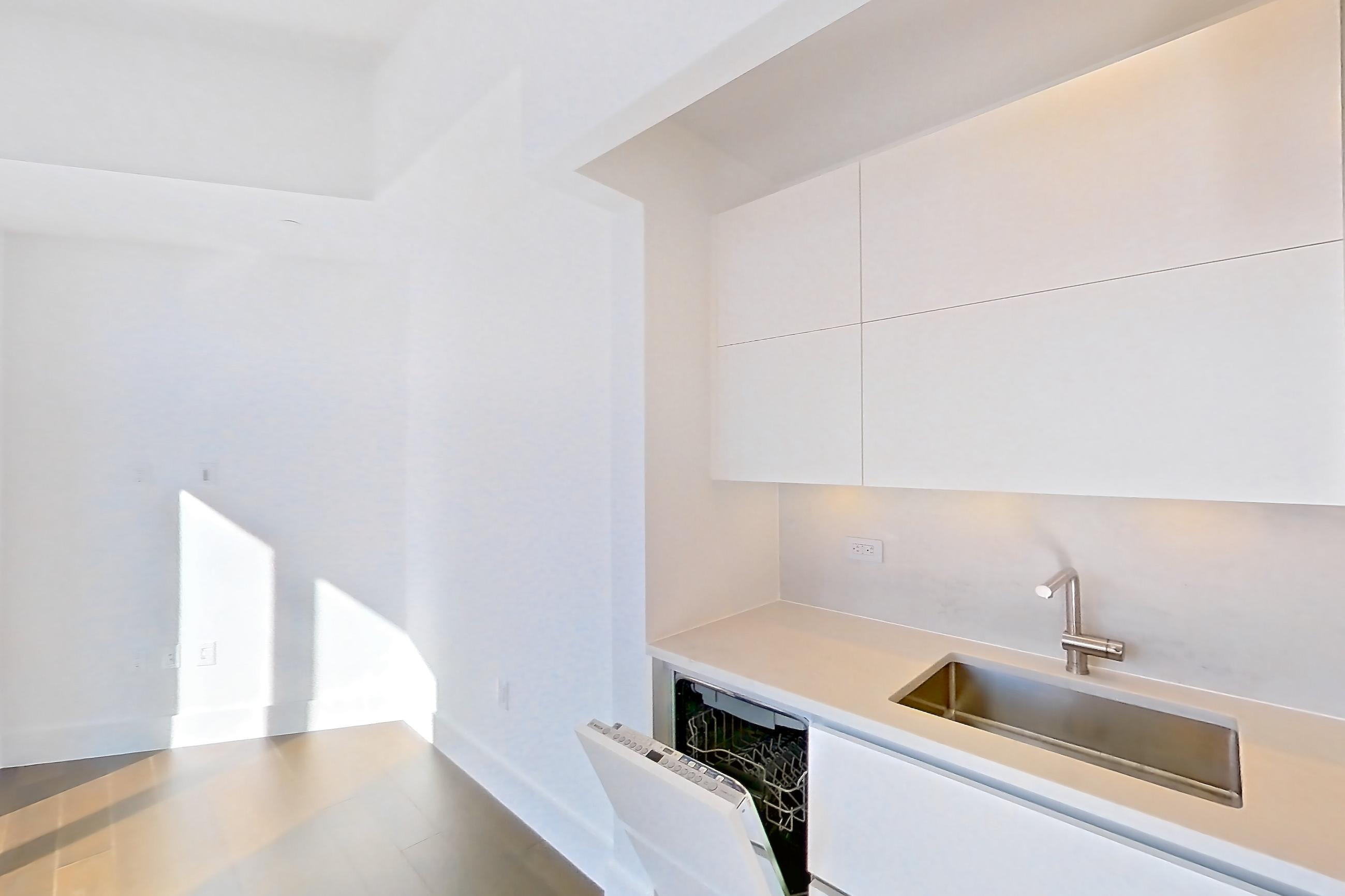 Kitchen with cooktop, dark wood-finish flooring, gas cooktop, light countertops, microwave, oven/range, refrigerator, stainless steel appliances, and white appliances, Apartment 40M at Summit NYC