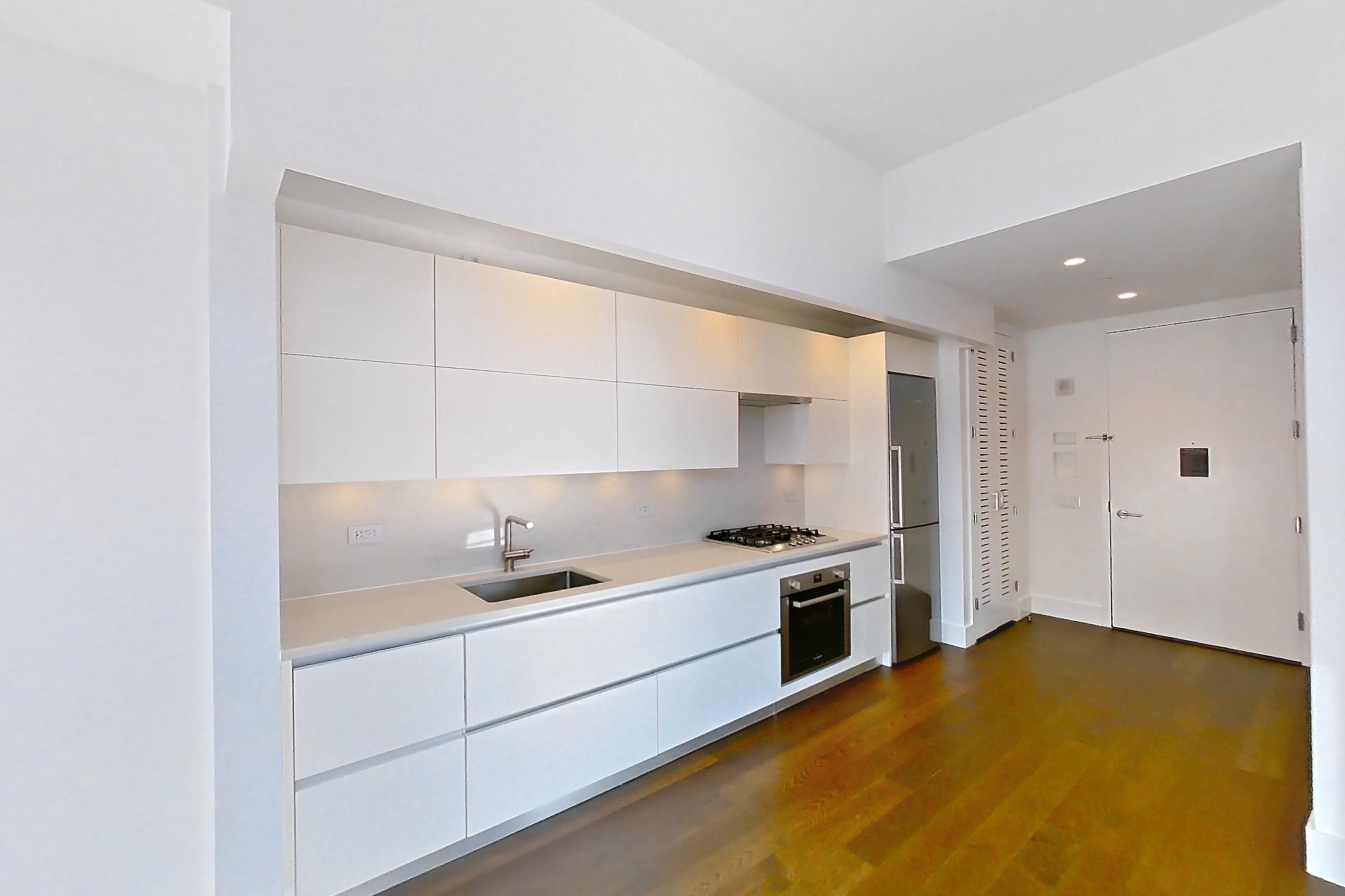 Living room with cooktop, dark wood-finish flooring, gas cooktop, light countertops, oven/range, refrigerator, stainless steel appliances, and wood-finish flooring, Apartment 40M at Summit NYC