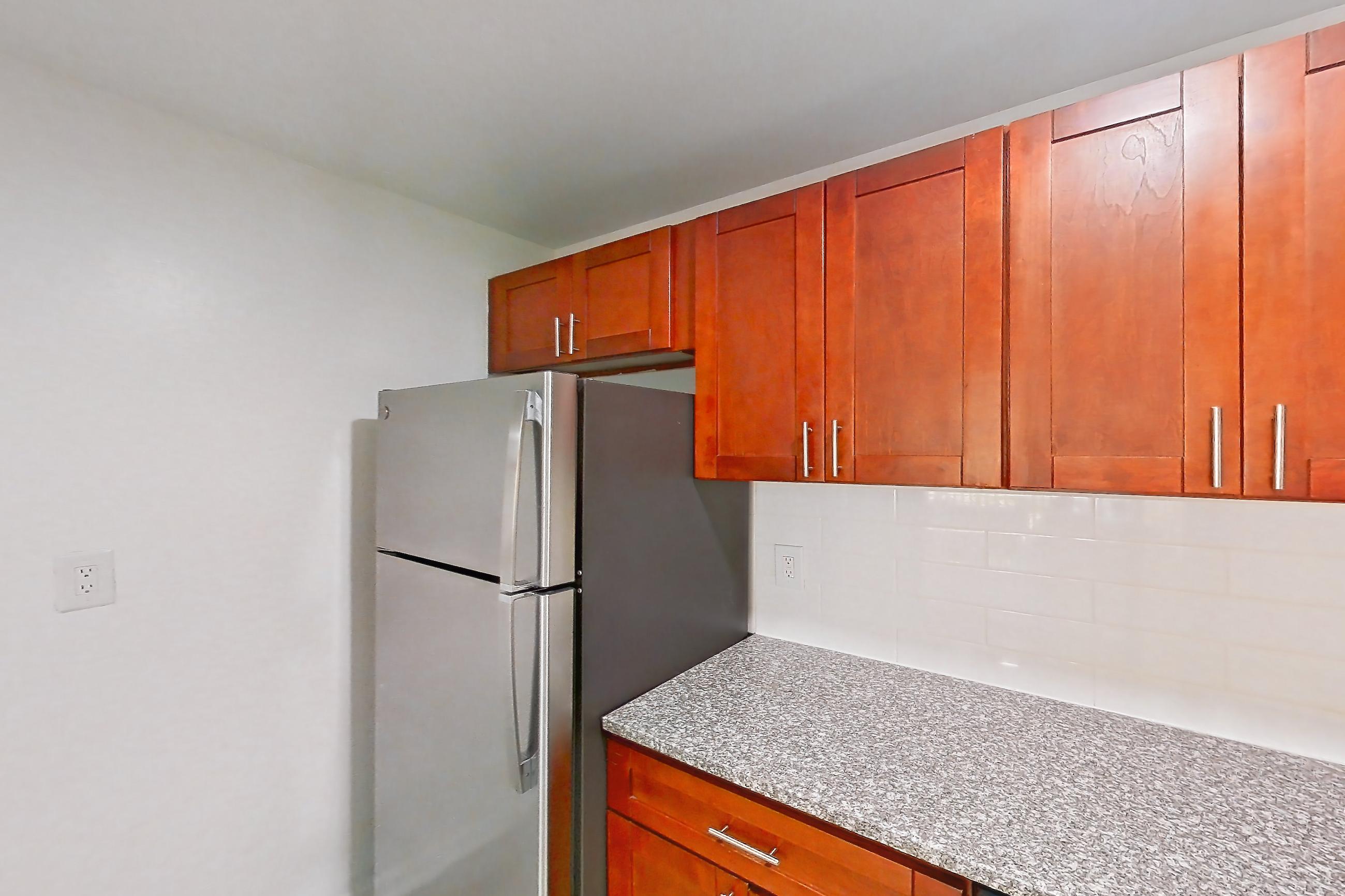 Kitchen with black appliances, dishwasher, gas range, light countertops, light stone countertops, light wood-finish flooring, oven/range, refrigerator, and stainless steel appliances, Apartment 9110ER22 at Franklin Park at Greenbelt Station