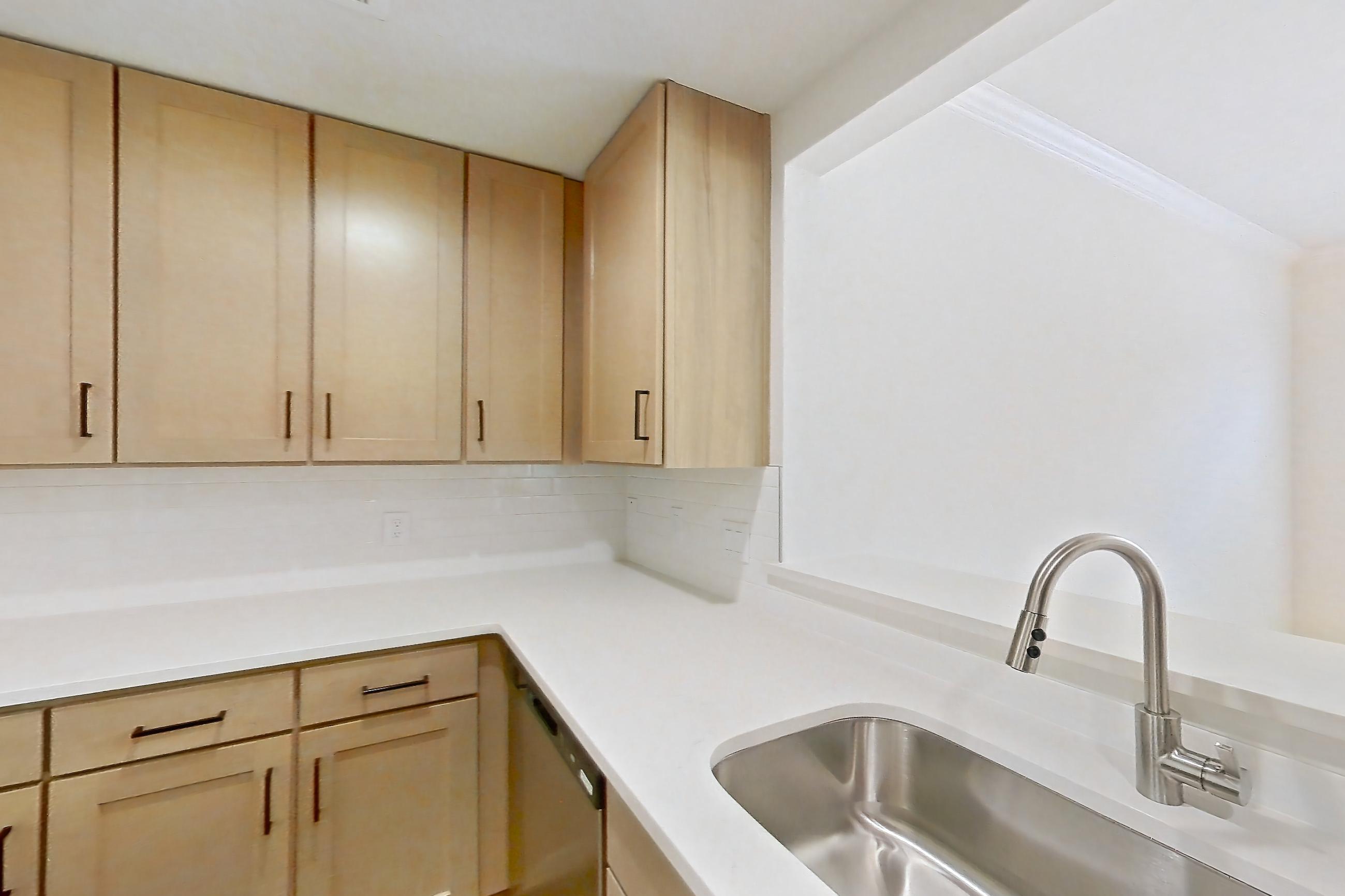 Kitchen with dishwasher, gas range, light countertops, light stone countertops, light wood-finish flooring, microwave, oven/range, and stainless steel appliances, Apartment 2411 at Marquis at Caprock Canyon
