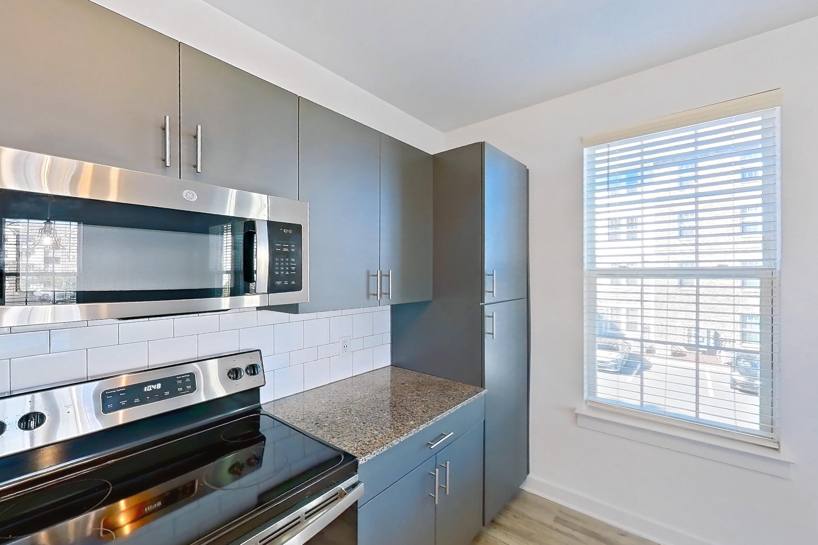 Kitchen with dishwasher, light stone countertops, light wood-finish flooring, oven/range, and stainless steel appliances, Apartment 1048-206 at Avril Cambridge Village