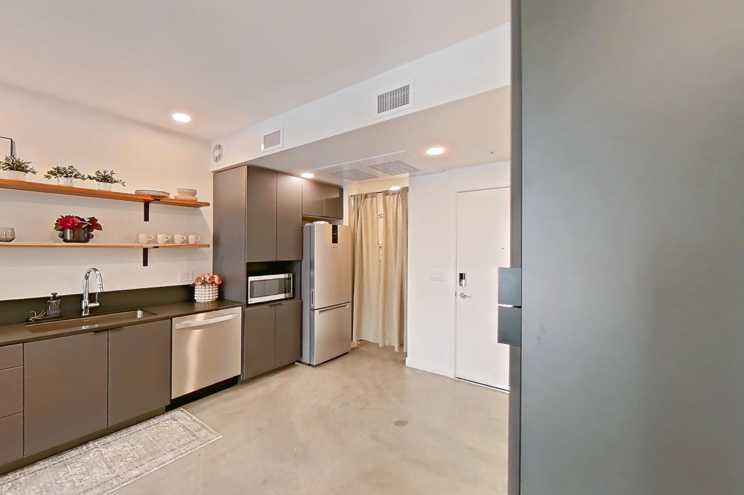 Dining room with in-unit laundry, light concrete flooring, polished concrete flooring, refrigerator, and white appliances, Apartment 2002 at Dwell @ 5th and Farmer
