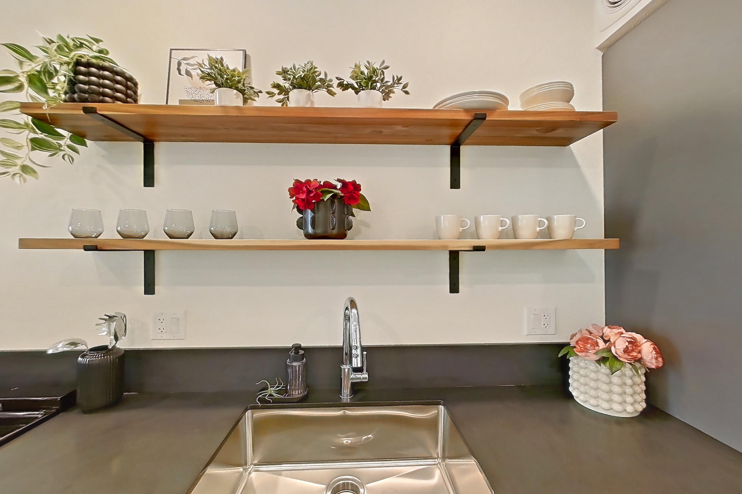 Kitchen with dark countertops, dishwasher, light concrete flooring, microwave, oven/range, polished concrete flooring, refrigerator, stainless steel appliances, and white appliances, Apartment 2002 at Dwell @ 5th and Farmer
