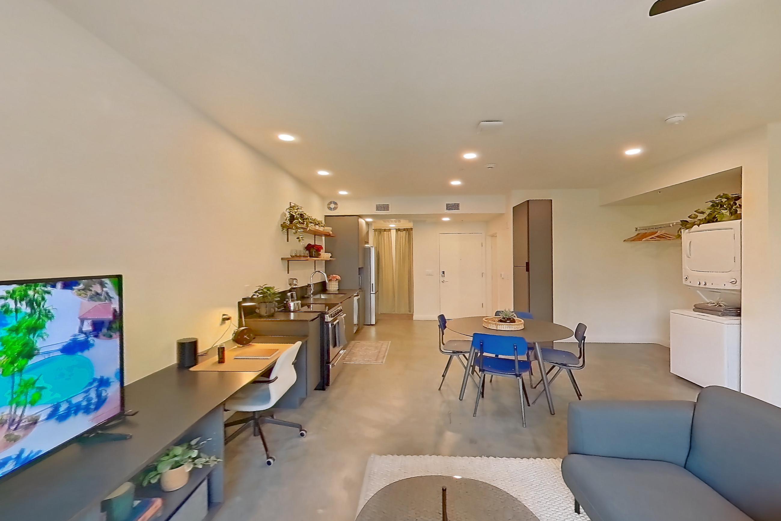 Living space with concrete flooring, light concrete flooring, oven/range, polished concrete flooring, refrigerator, stainless steel appliances, and white appliances, Apartment 2002 at Dwell @ 5th and Farmer