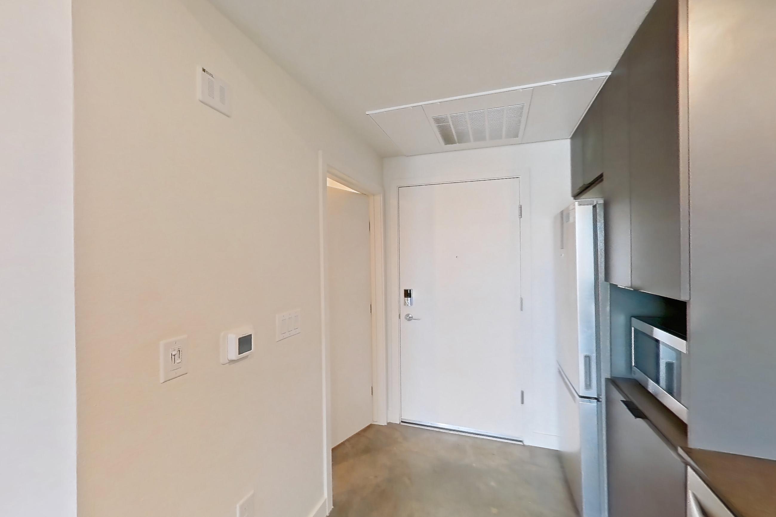 Kitchen with dark countertops, dishwasher, electric range, in-unit laundry, microwave, oven/range, polished concrete flooring, refrigerator, stainless steel appliances, and white appliances, Apartment 2060 at Dwell @ 5th and Farmer