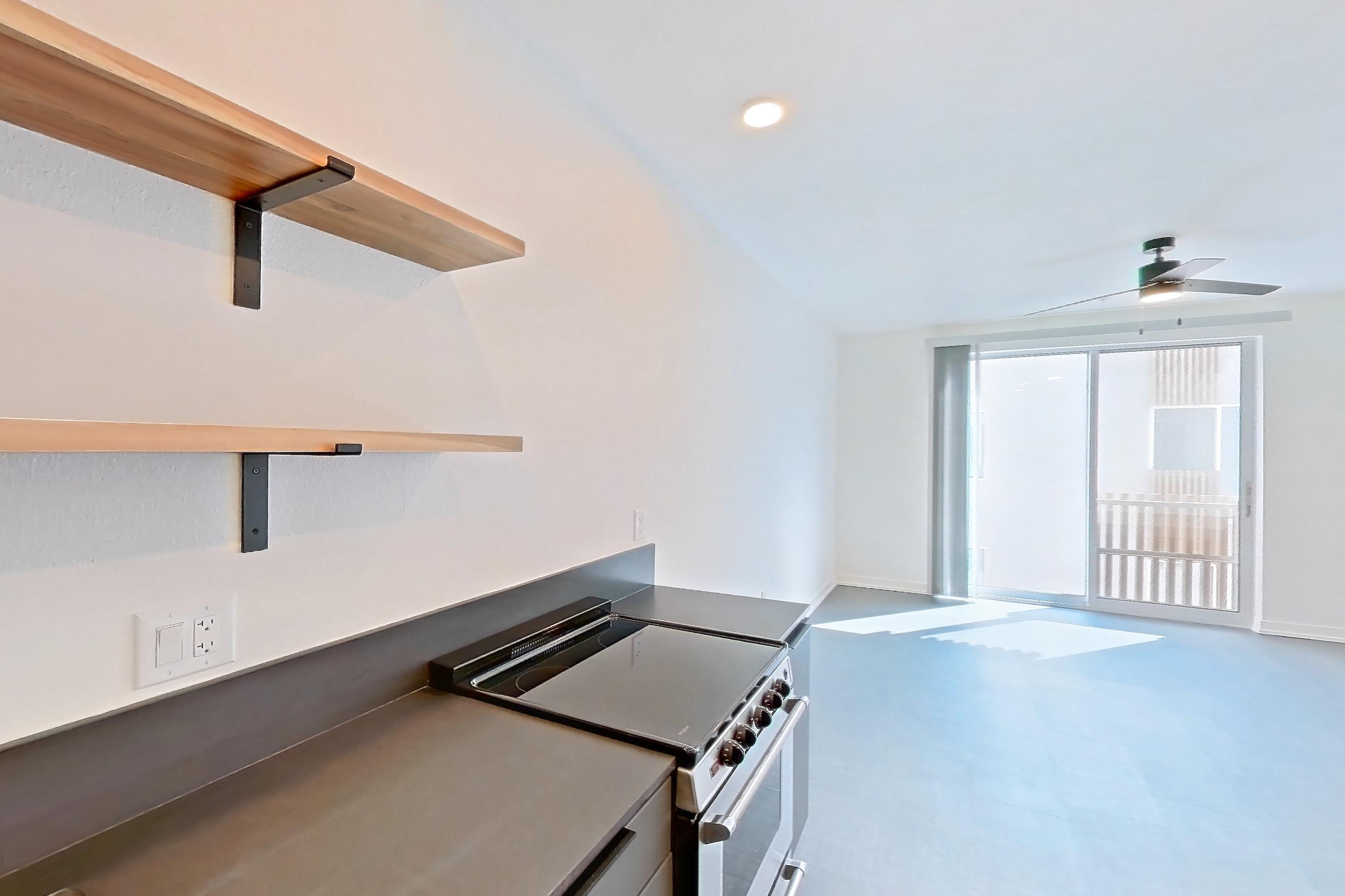Kitchen with dark countertops, dishwasher, electric range, light carpet, microwave, oven/range, refrigerator, stainless steel appliances, and white appliances, Apartment 3031 at Dwell @ 5th and Farmer