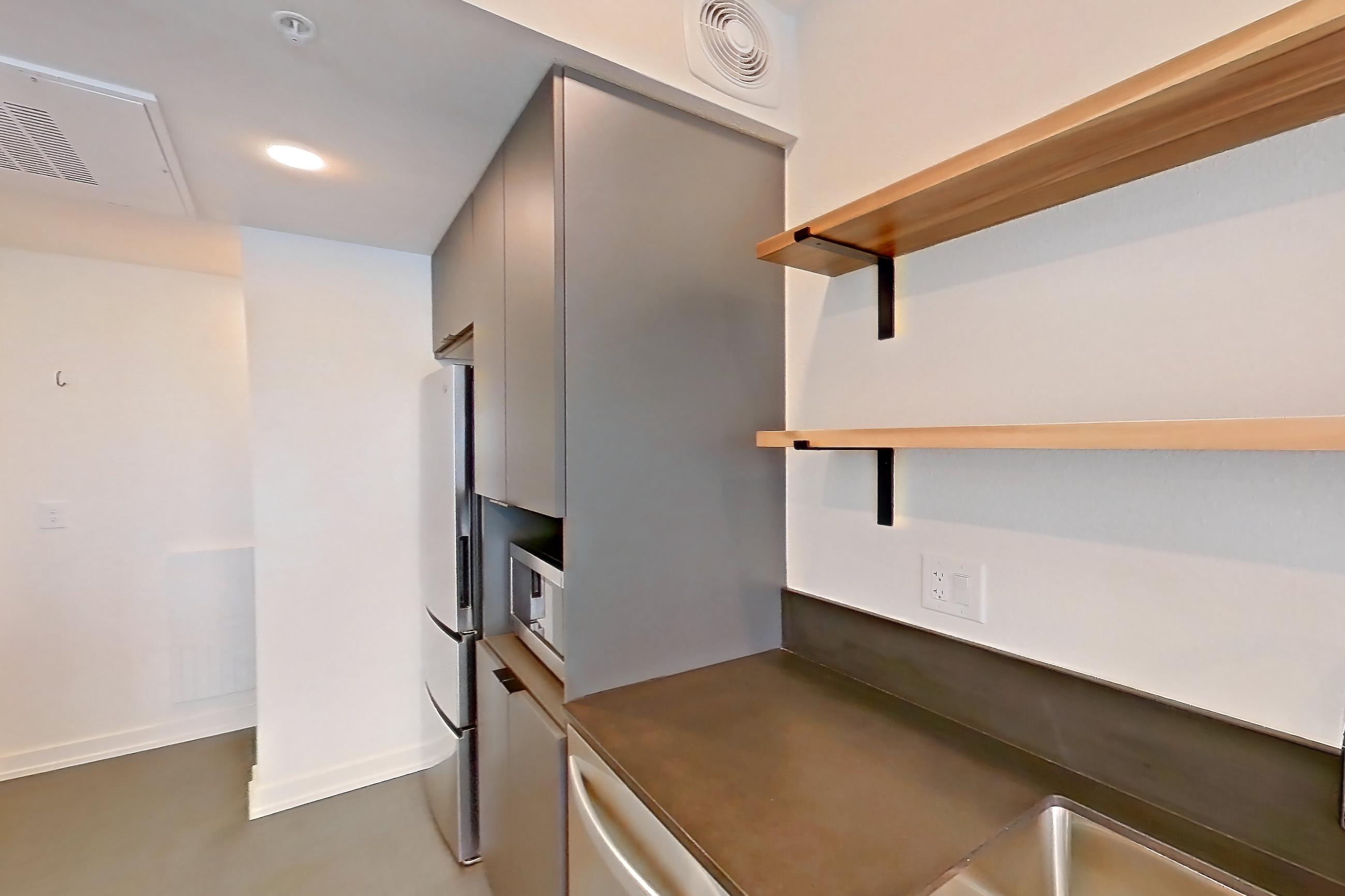 Kitchen with dark countertops, dishwasher, electric range, light carpet, microwave, oven/range, refrigerator, stainless steel appliances, and white appliances, Apartment 3031 at Dwell @ 5th and Farmer