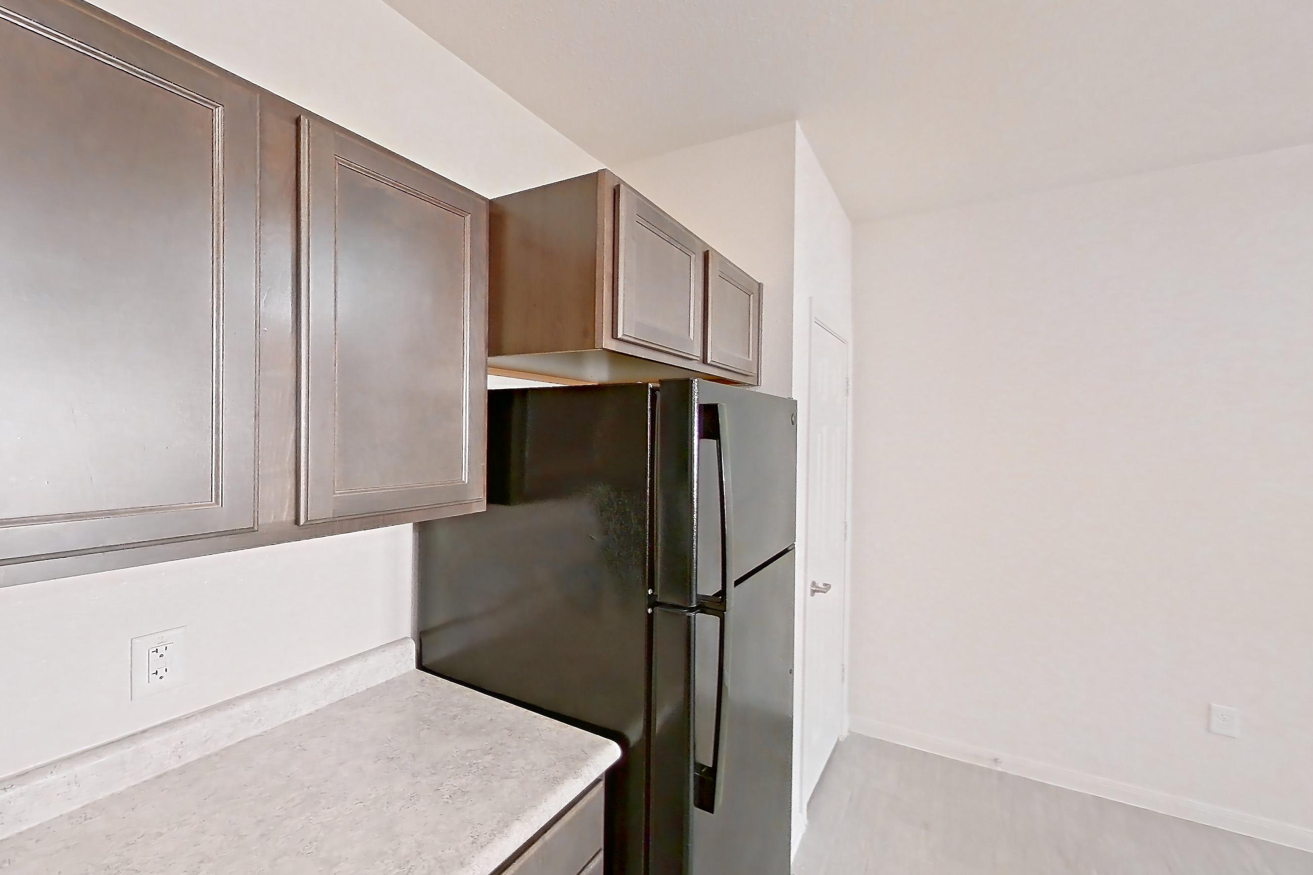 Kitchen with black appliances, electric range, light countertops, light wood-finish flooring, microwave, oven/range, and refrigerator, Apartment 3202 at Residences of Stillwater