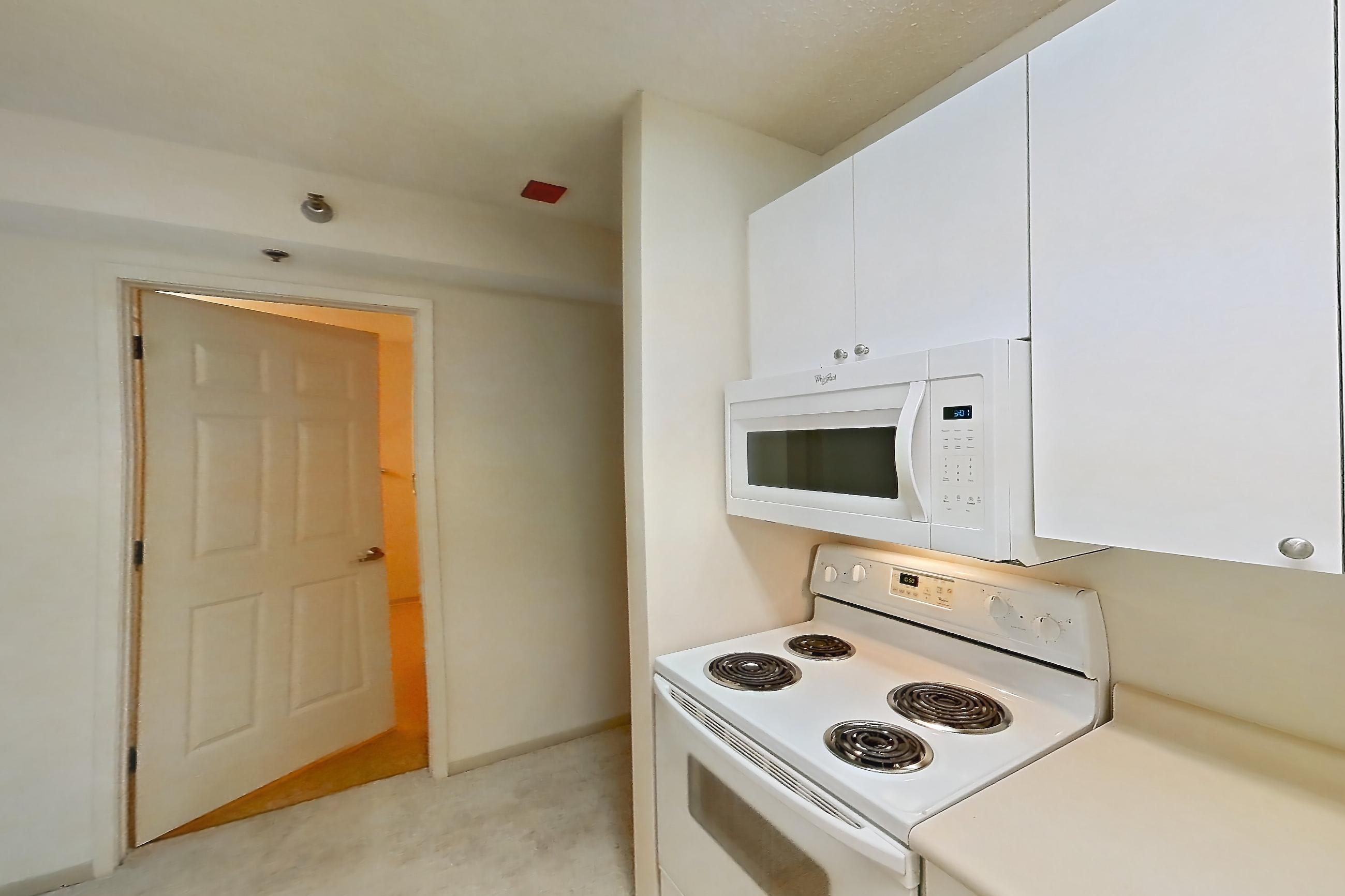 Kitchen with dishwasher, electric range, light countertops, light vinyl flooring, microwave, oven/range, and white appliances, Apartment 802 at Sky55
