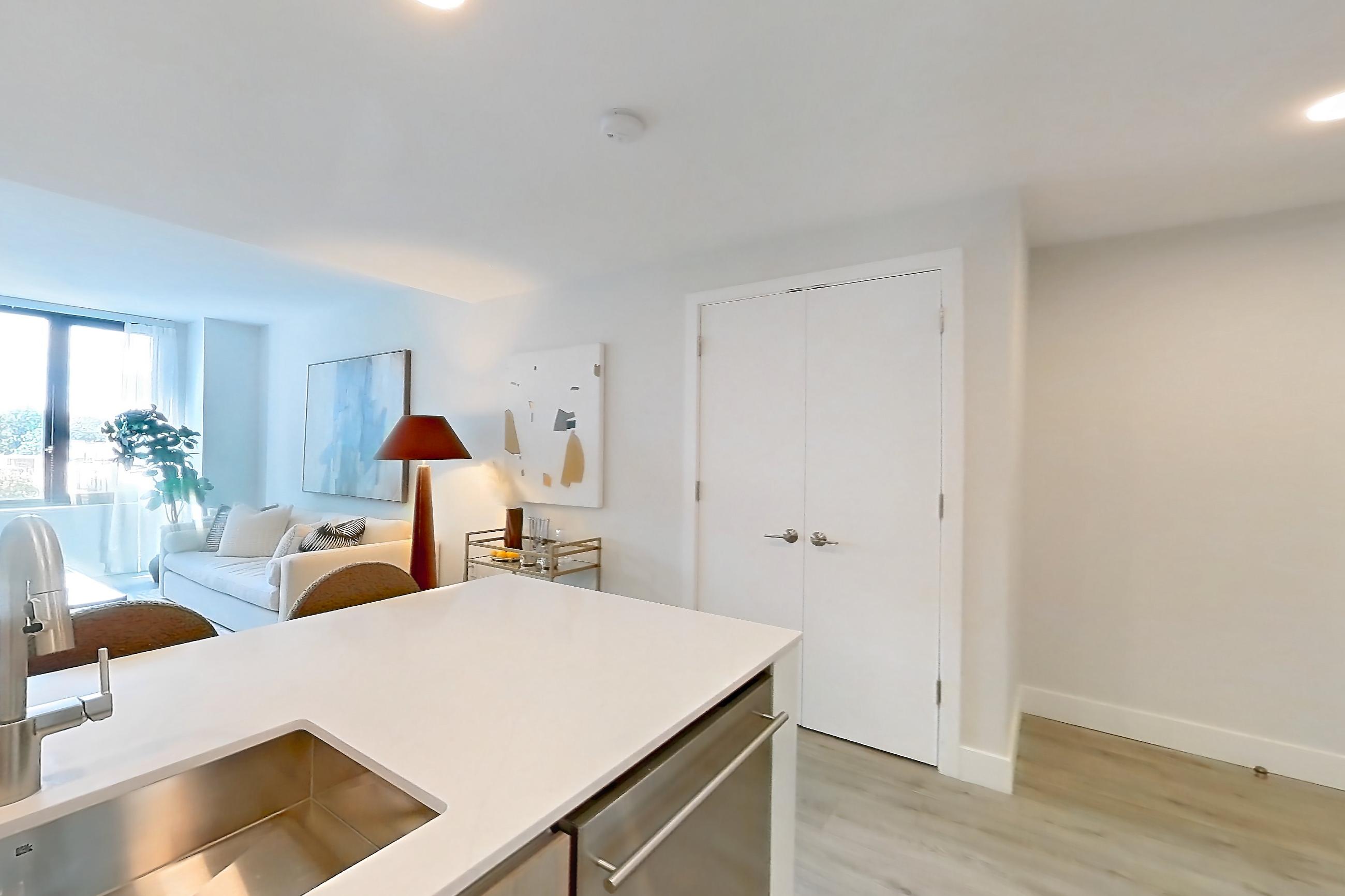 Kitchen with dishwasher, gas range, light countertops, light stone countertops, light wood-finish flooring, microwave, oven/range, refrigerator, and stainless steel appliances, Apartment 924 at Loden