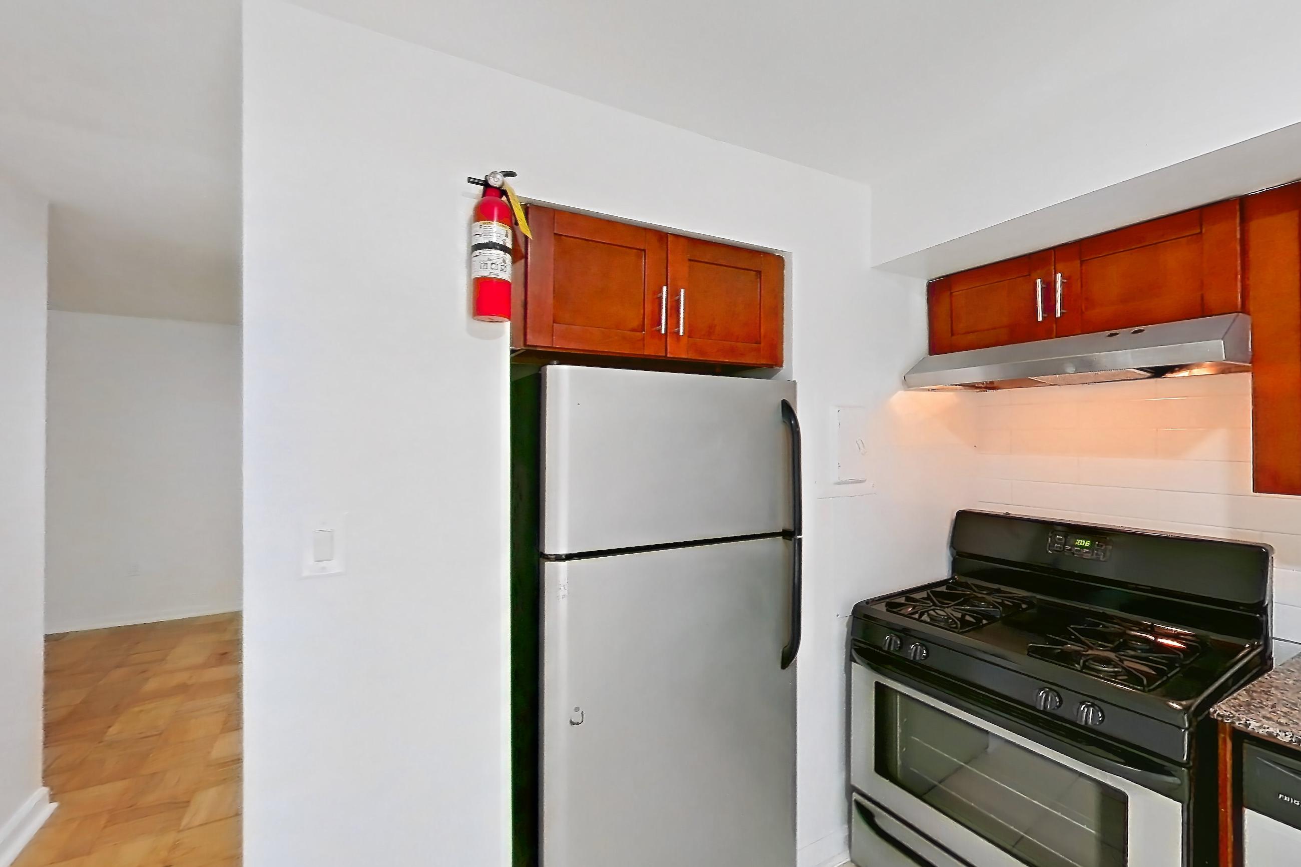 Kitchen with dark stone countertops, dishwasher, gas range, light tile flooring, oven/range, range hood, refrigerator, stainless steel appliances, and white appliances, Apartment 5801CL32 at Franklin Park at Greenbelt Station