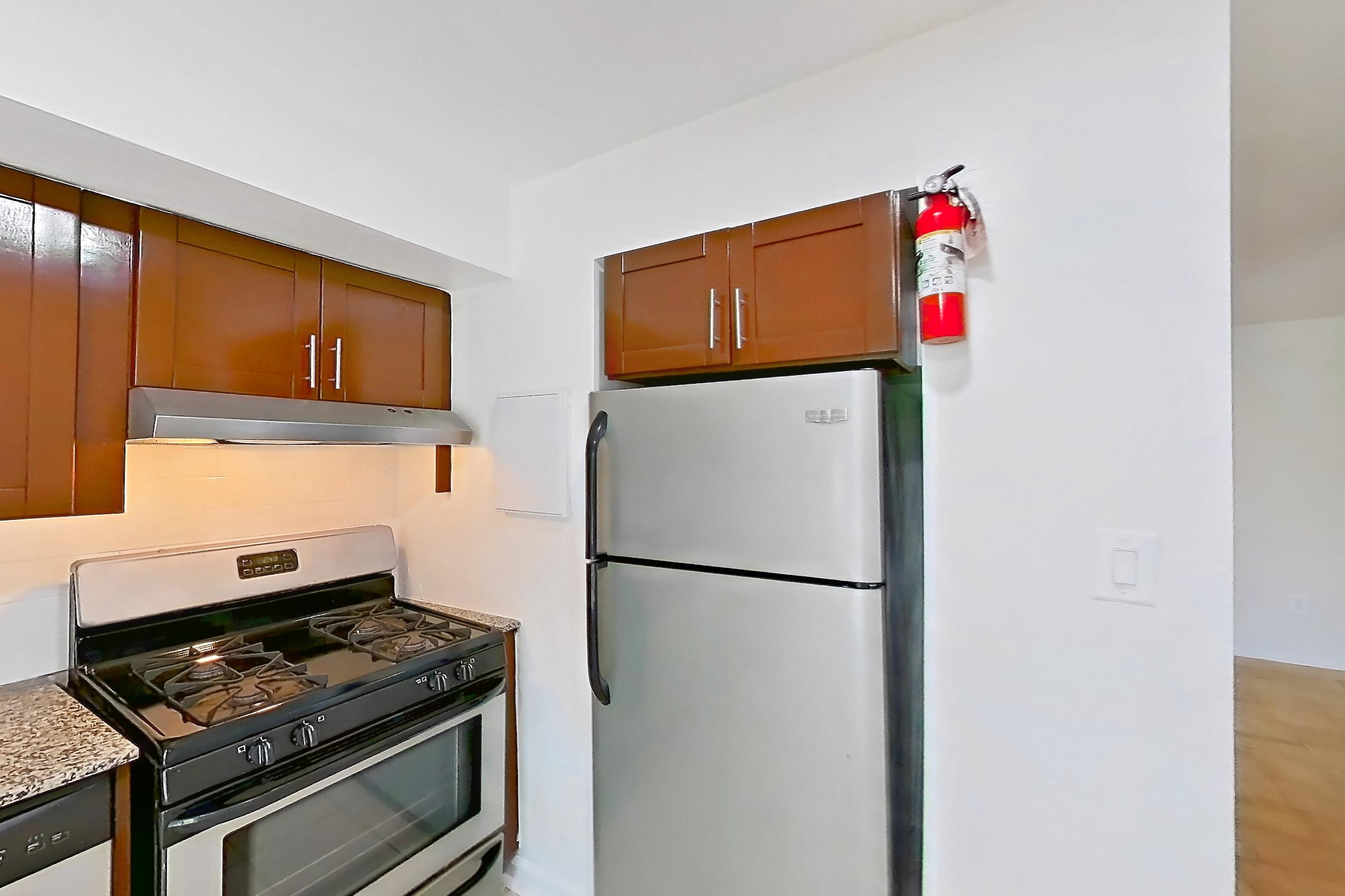 Kitchen with dishwasher, gas range, light countertops, light stone countertops, light tile flooring, oven/range, refrigerator, and stainless steel appliances, Apartment 5805CL33 at Franklin Park at Greenbelt Station