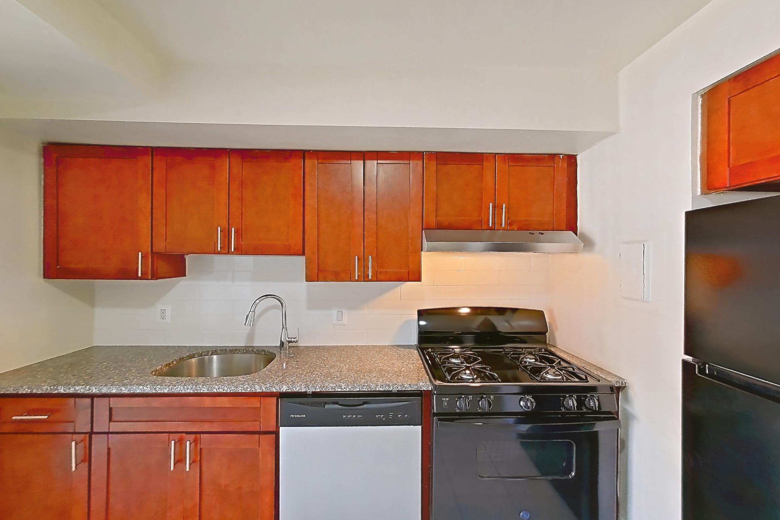 Kitchen with black appliances, dark stone countertops, dishwasher, gas range, light countertops, light tile flooring, oven/range, range hood, refrigerator, and stainless steel appliances, Apartment 5813CL31 at Franklin Park at Greenbelt Station