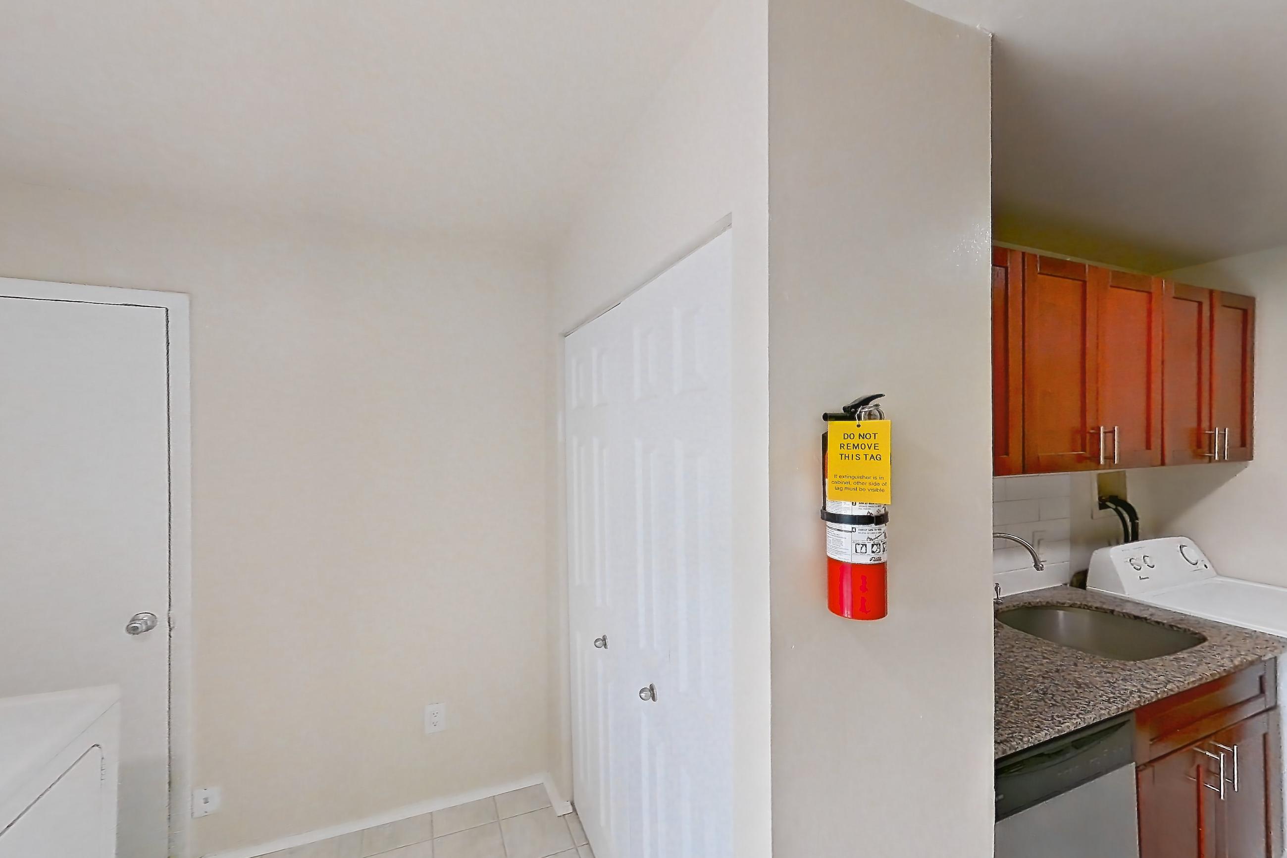 Kitchen with black appliances, dark stone countertops, dishwasher, gas range, in-unit laundry, light countertops, light tile flooring, oven/range, refrigerator, and stainless steel appliances, Apartment 9328ER31 at Franklin Park at Greenbelt Station