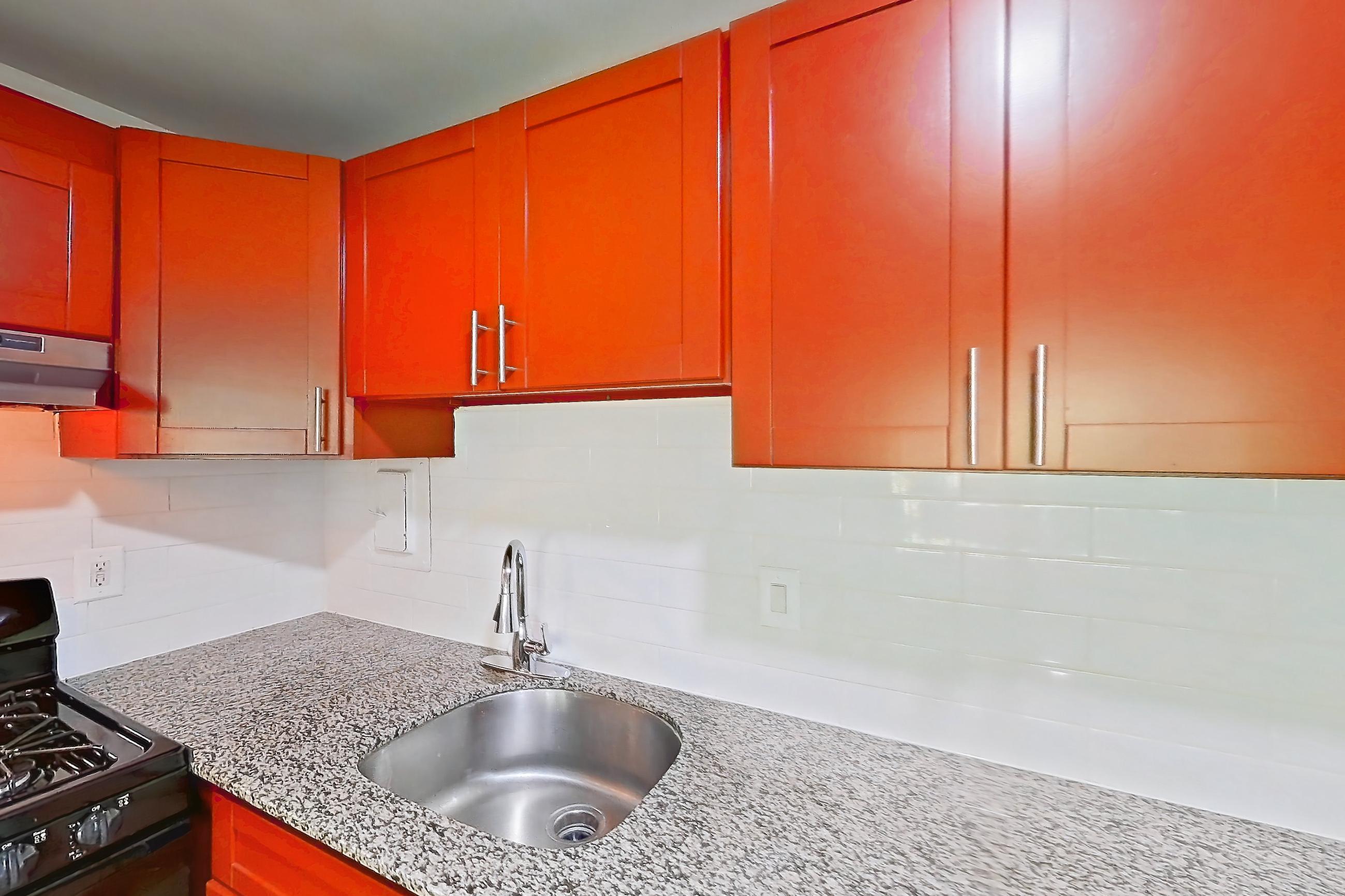Kitchen with black appliances, dishwasher, gas range, light countertops, light stone countertops, light wood-finish flooring, oven/range, range hood, and stainless steel appliances, Apartment 5919CT34 at Franklin Park at Greenbelt Station
