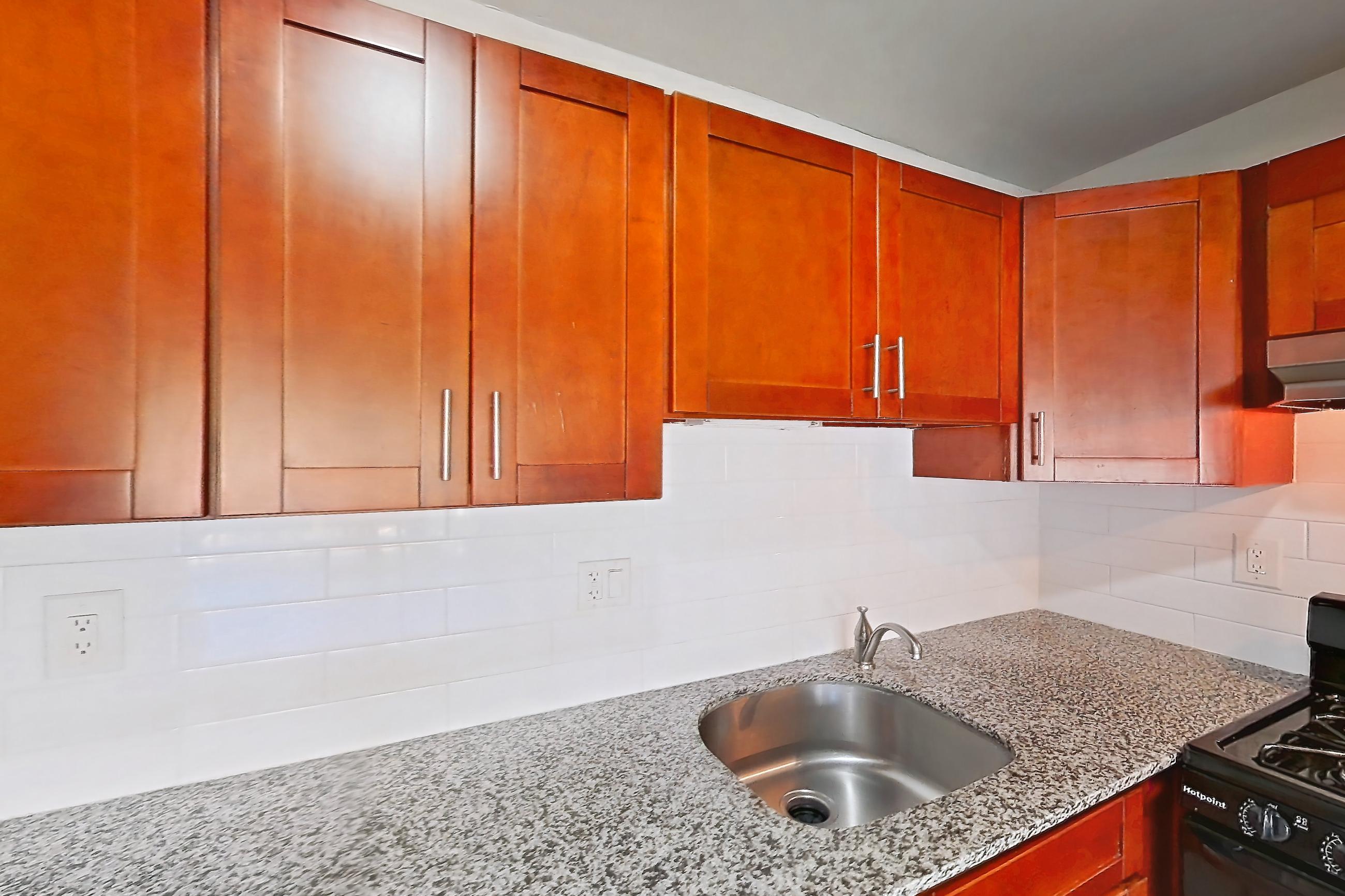Kitchen with black appliances, dishwasher, gas range, light countertops, light stone countertops, light tile flooring, oven/range, range hood, and stainless steel appliances, Apartment 5925CT32 at Franklin Park at Greenbelt Station