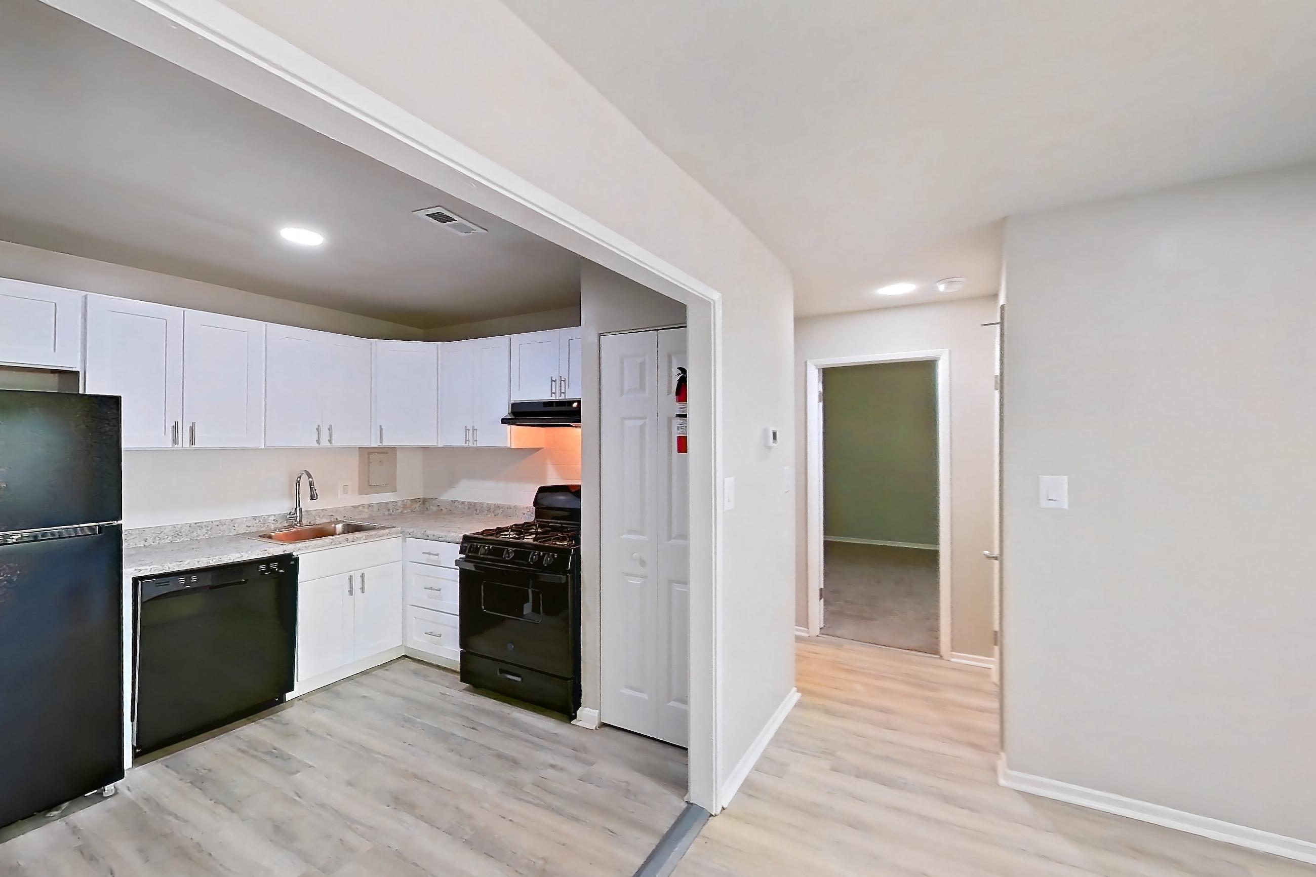 Living room with black appliances, gas range, light countertops, light wood-finish flooring, and oven/range, Apartment 6124BD32 at Franklin Park at Greenbelt Station