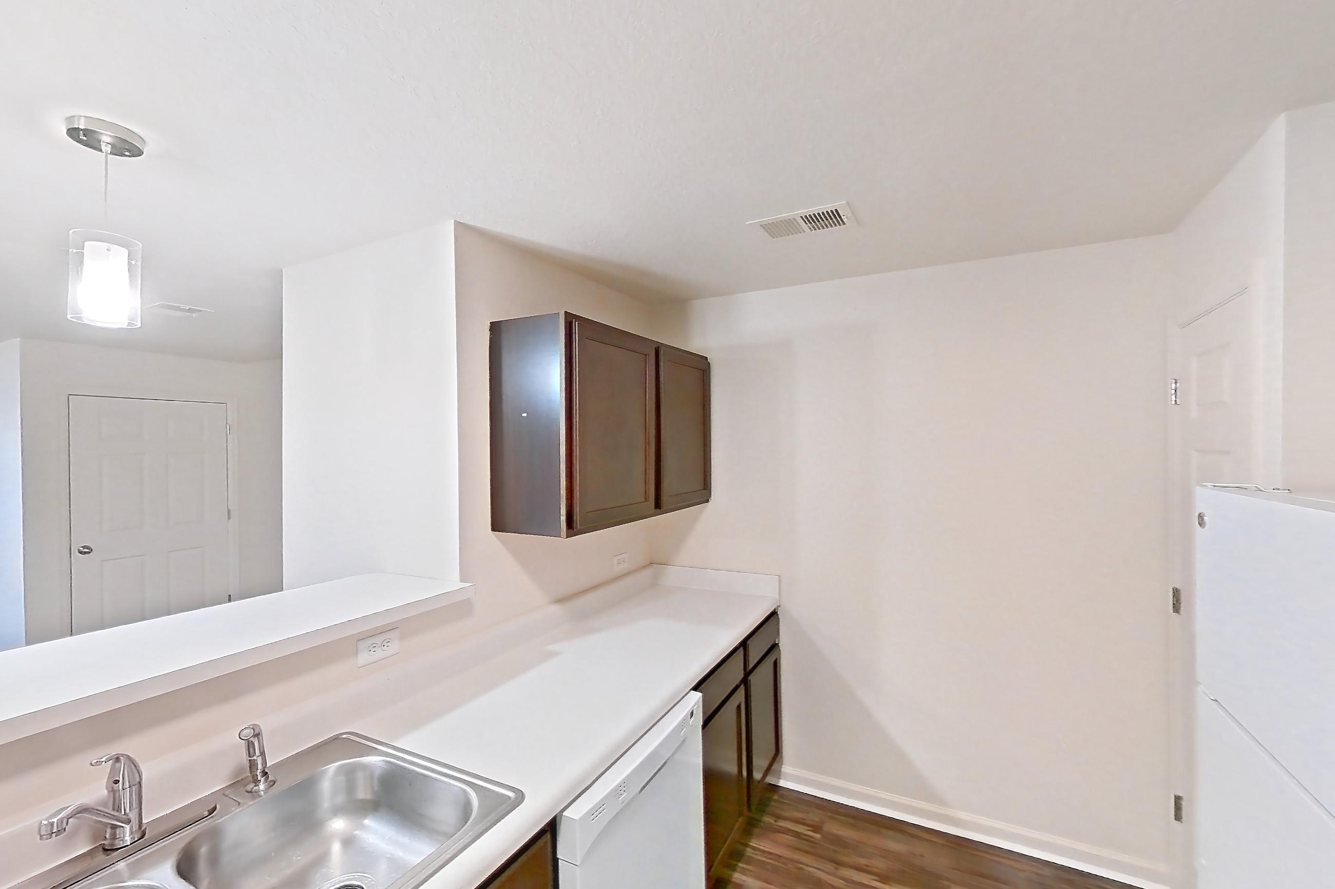 Kitchen with dark wood-finish flooring, dishwasher, electric range, light countertops, oven/range, range hood, refrigerator, and white appliances, Apartment 6481-104 at Ashley Estates