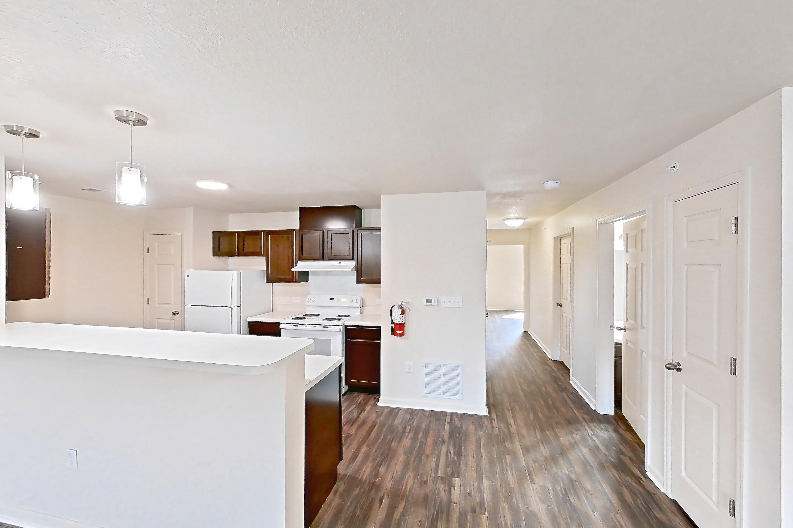 Living space with dark wood-finish flooring, electric range, light countertops, oven/range, refrigerator, and white appliances, Apartment 6481-104 at Ashley Estates