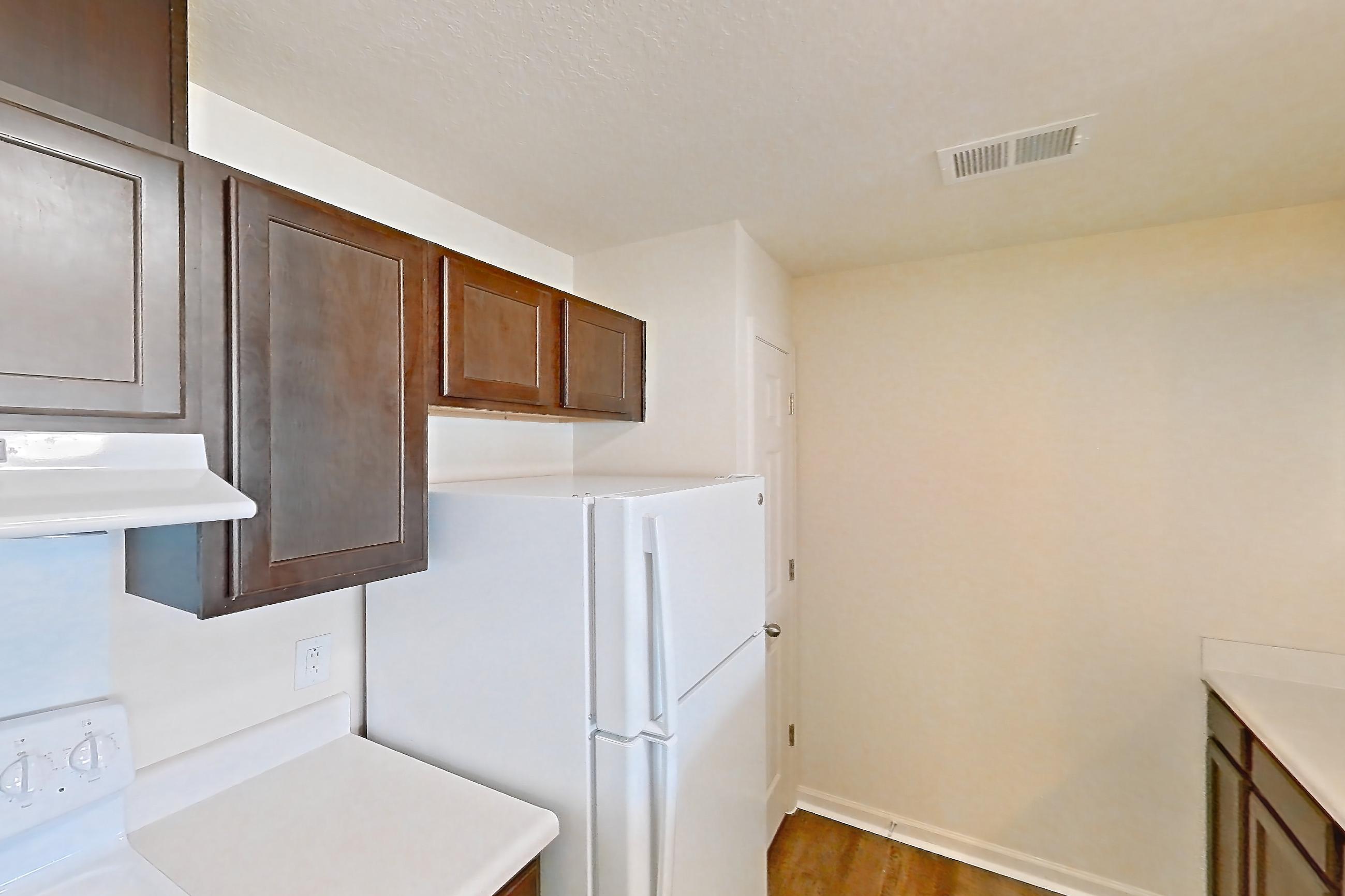 Kitchen with dark carpet, dark wood-finish flooring, dishwasher, electric range, light countertops, oven/range, range hood, refrigerator, and white appliances, Apartment 6421-206 at Ashley Estates