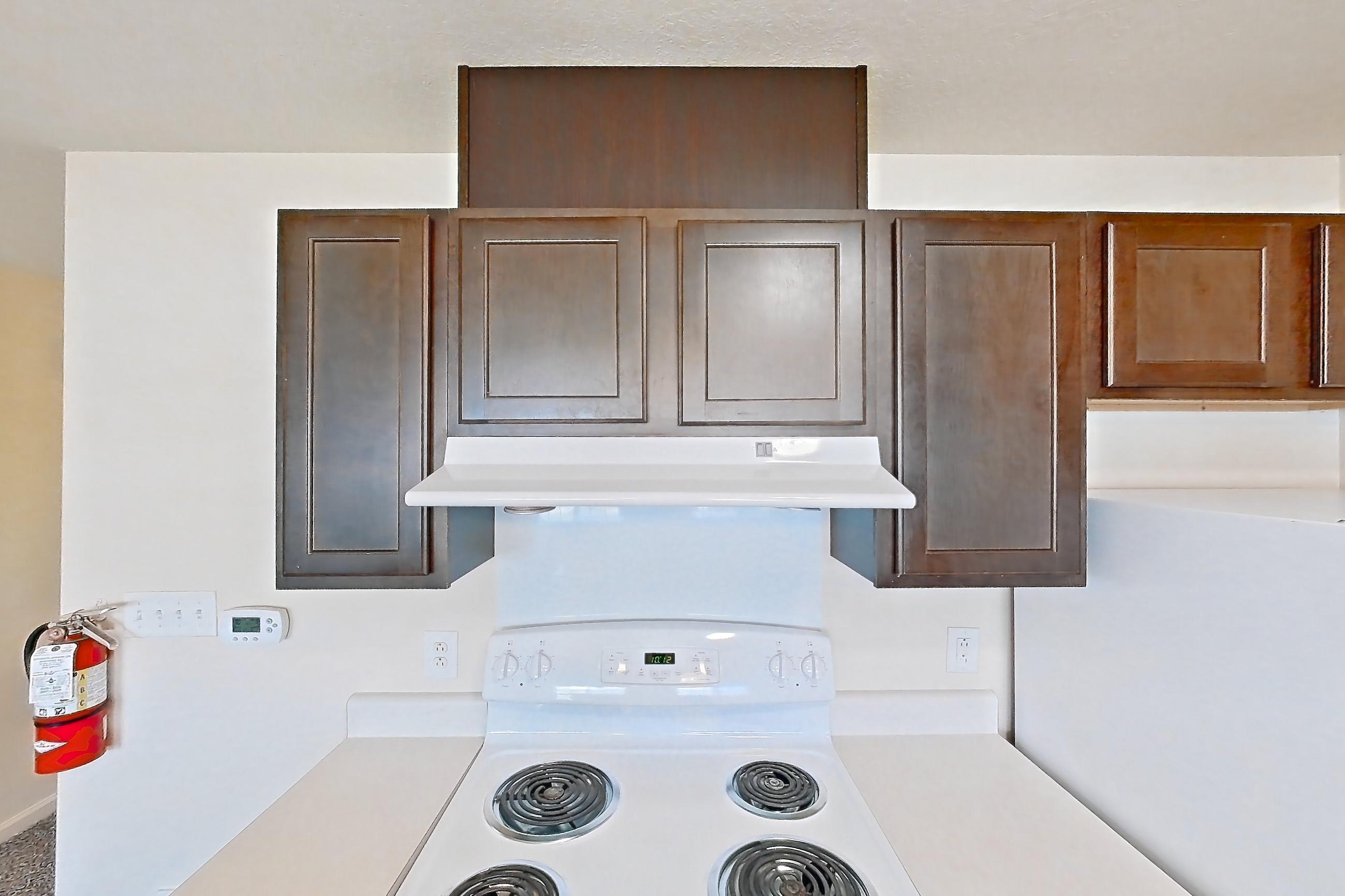Kitchen with dark carpet, dark wood-finish flooring, dishwasher, electric range, light countertops, oven/range, range hood, refrigerator, and white appliances, Apartment 6421-206 at Ashley Estates