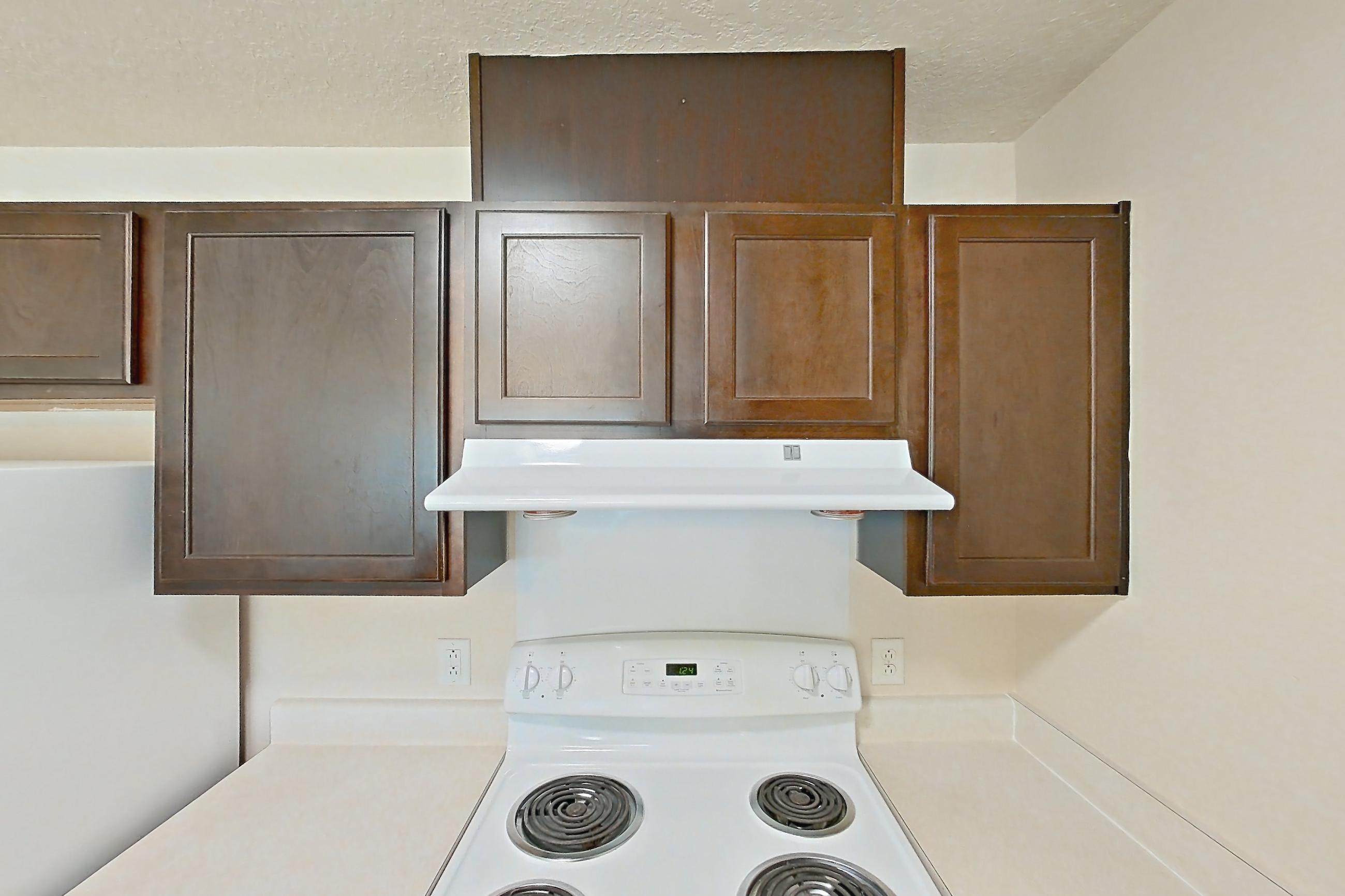 Kitchen with dark wood-finish flooring, dishwasher, electric range, light countertops, oven/range, refrigerator, and white appliances, Apartment 6469-206 at Ashley Estates
