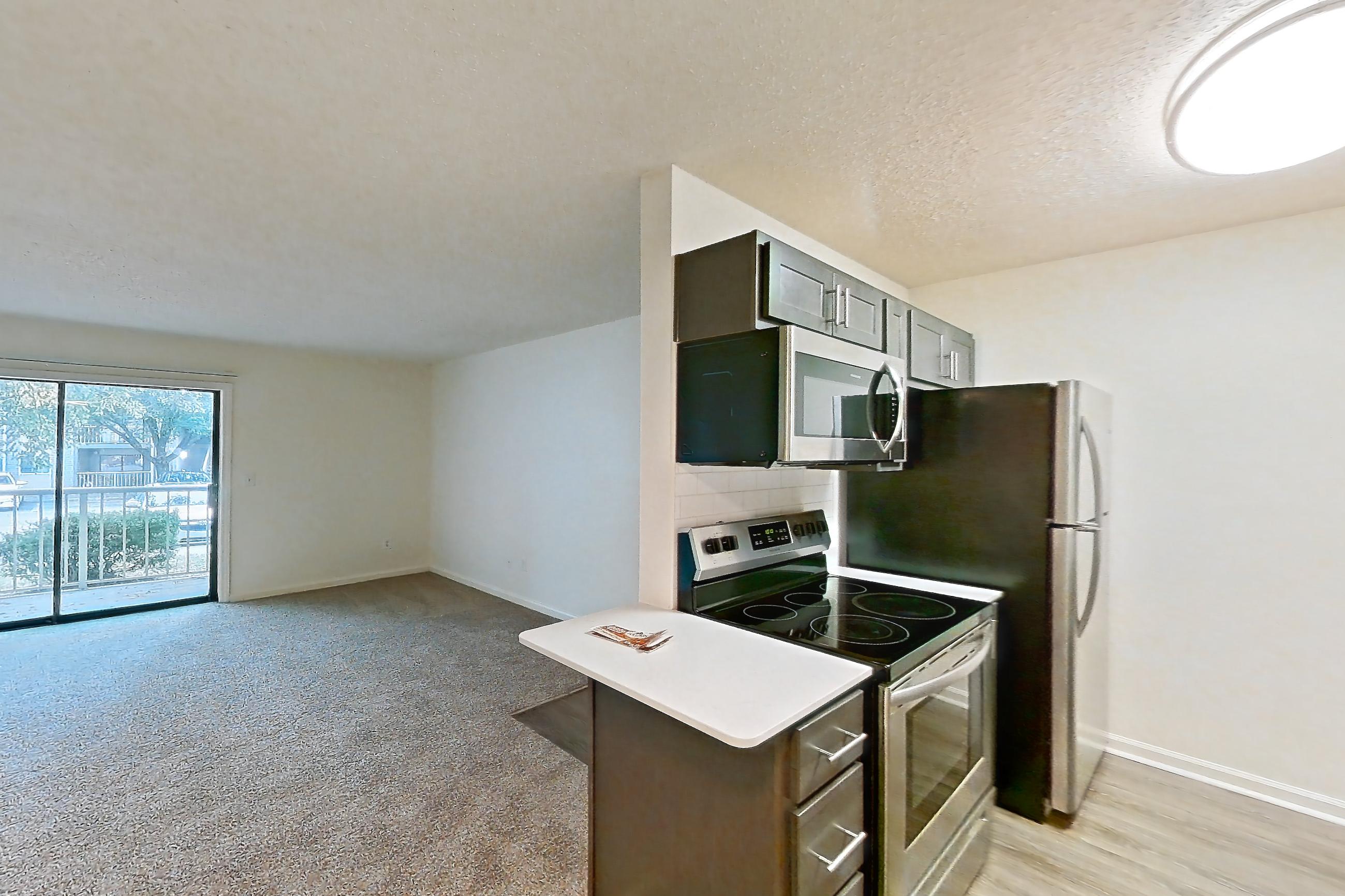 Dining room with electric range, light carpet, light countertops, light stone countertops, light wood-finish flooring, microwave, oven/range, refrigerator, and stainless steel appliances, Apartment 68104 at The Boulders