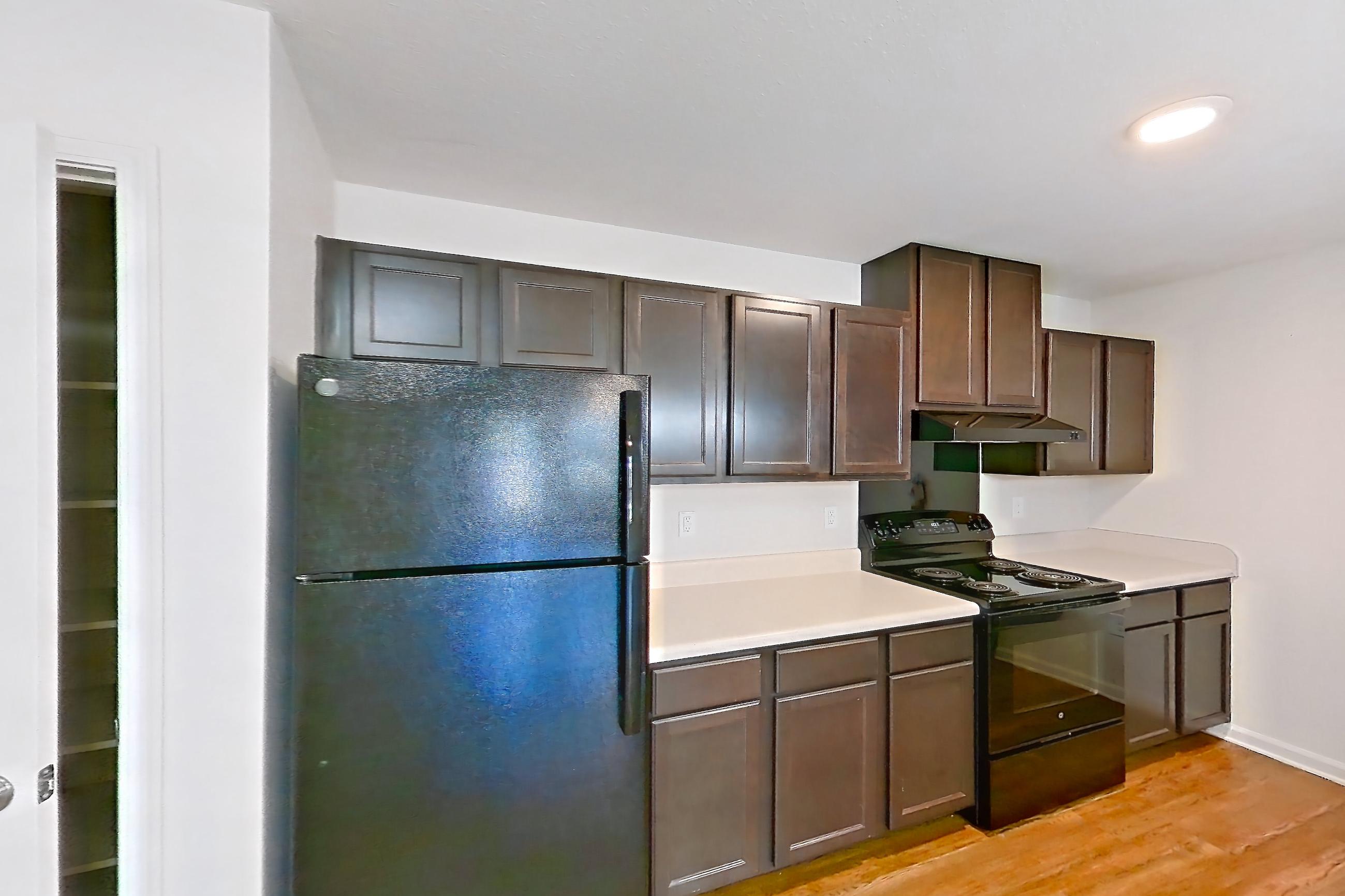 Dining room with black appliances, dark wood-finish flooring, light countertops, light wood-finish flooring, and refrigerator, Apartment 8212 Unit 105 at The HUB on Harris