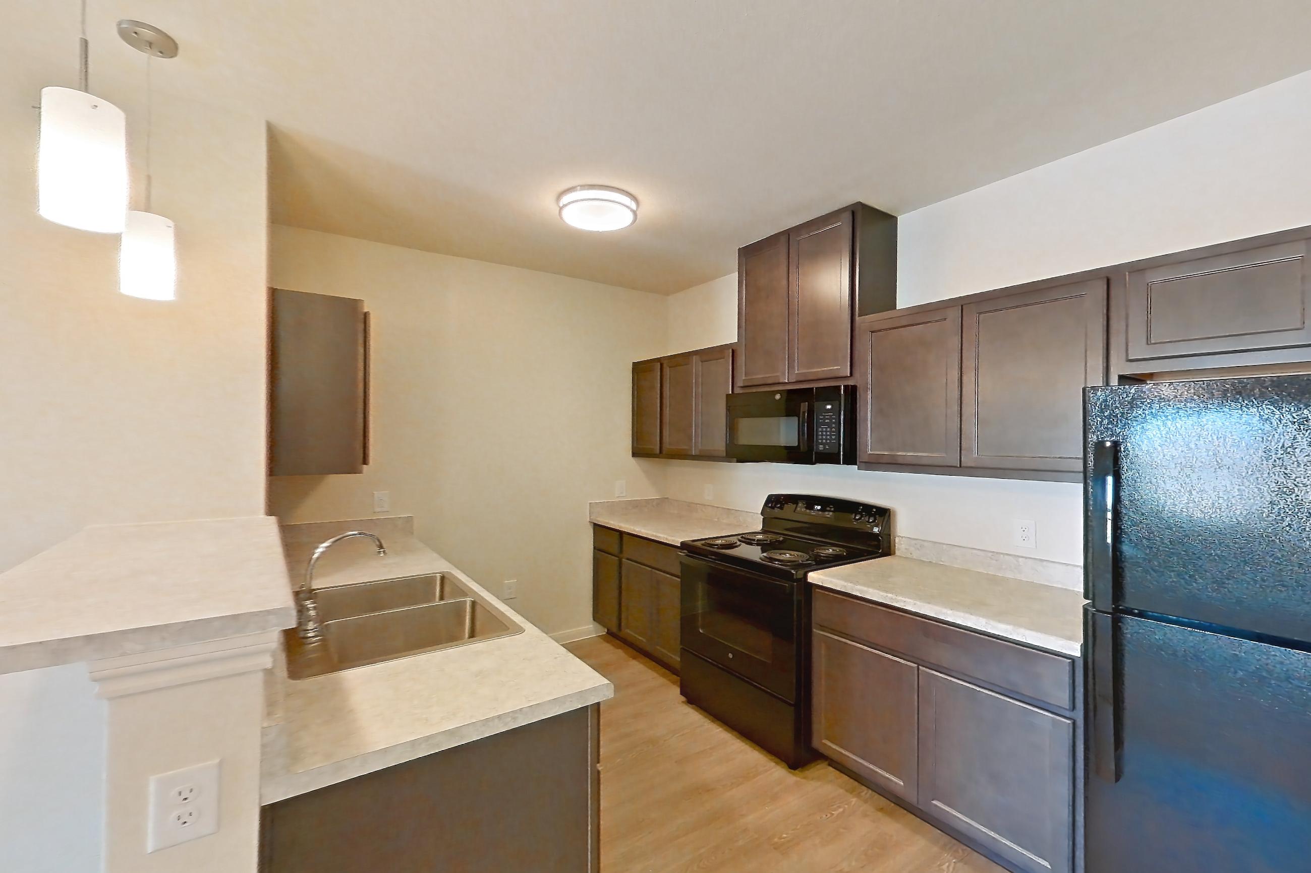 Dining room with black appliances, electric range, light carpet, light countertops, light wood-finish flooring, and oven/range, Apartment 7208 at Mill Stream