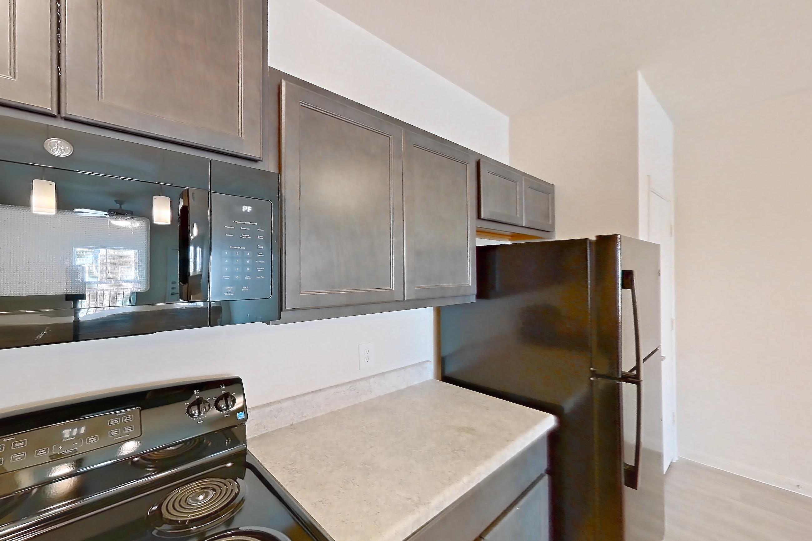 Kitchen with black appliances, dishwasher, electric range, light countertops, light wood-finish flooring, oven/range, and refrigerator, Apartment 7208 at Mill Stream
