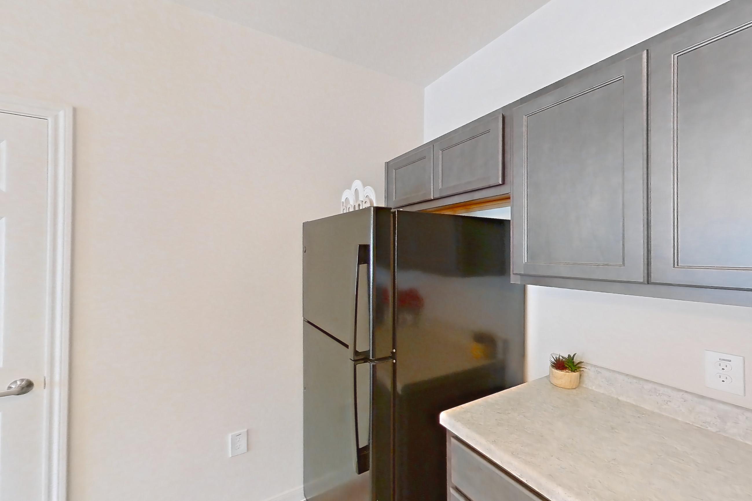 Kitchen with black appliances, dishwasher, electric range, light countertops, light wood-finish flooring, oven/range, refrigerator, and stainless steel appliances, Apartment 3101 at Mill Stream