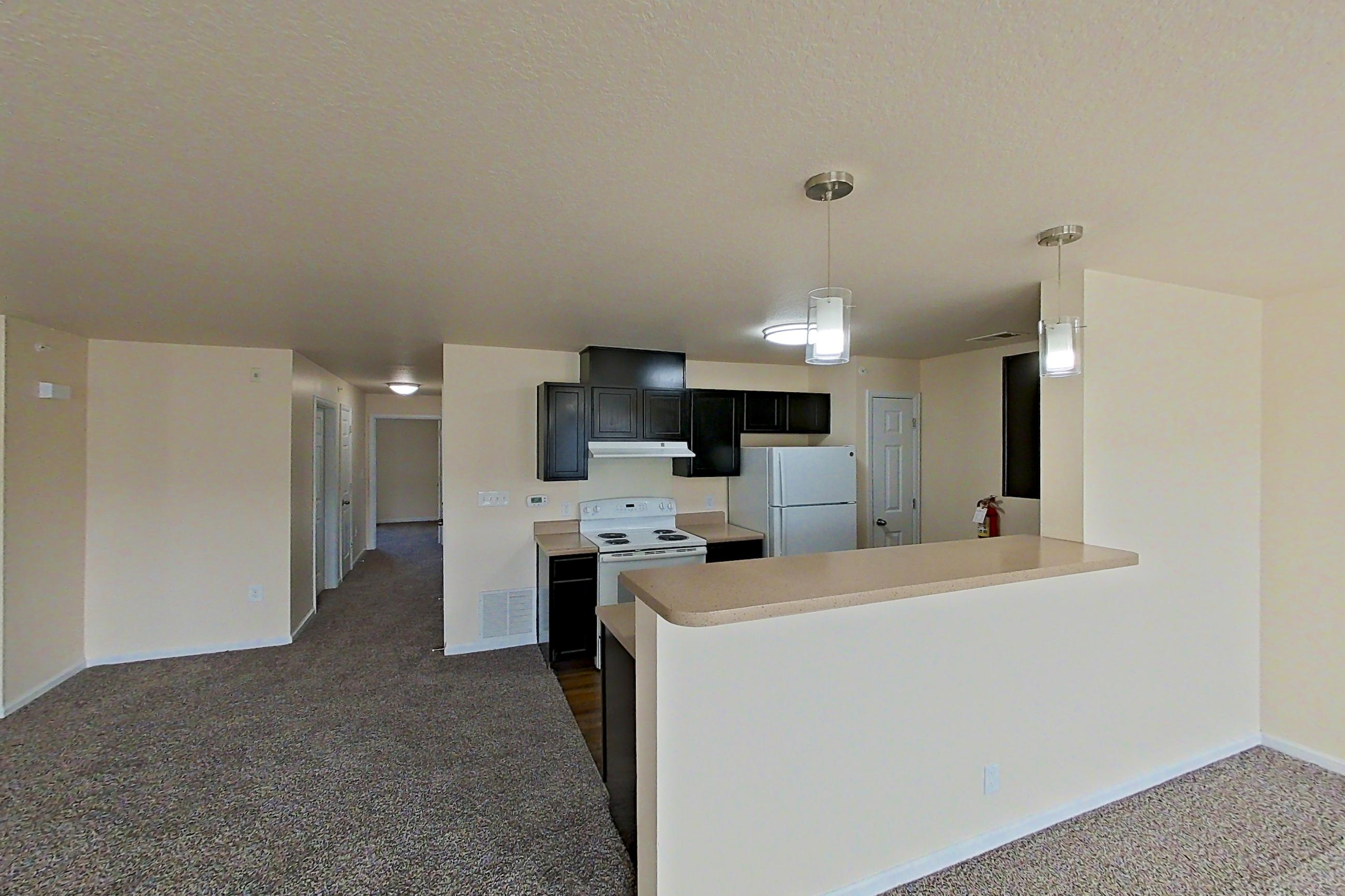 Living space with dark carpet, electric range, light countertops, oven/range, refrigerator, and white appliances, Apartment 19573 E 57th Ave - Unit 204 at The Meadows at Dunkirk