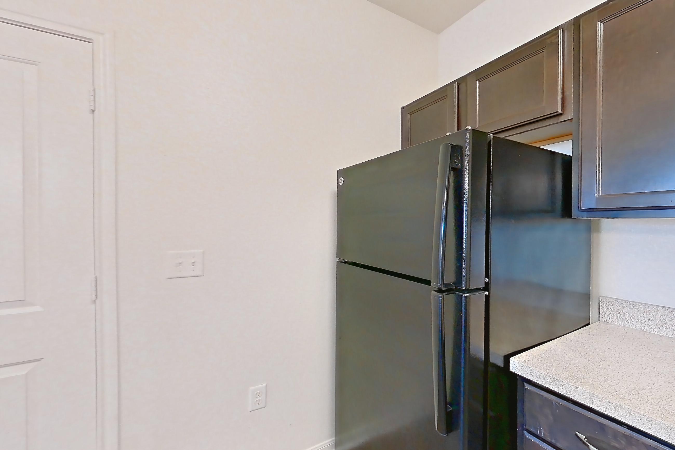 Kitchen with black appliances, dark wood-finish flooring, dishwasher, electric range, light countertops, oven/range, refrigerator, and stainless steel appliances, Apartment 1314 at The Heights on Parmer