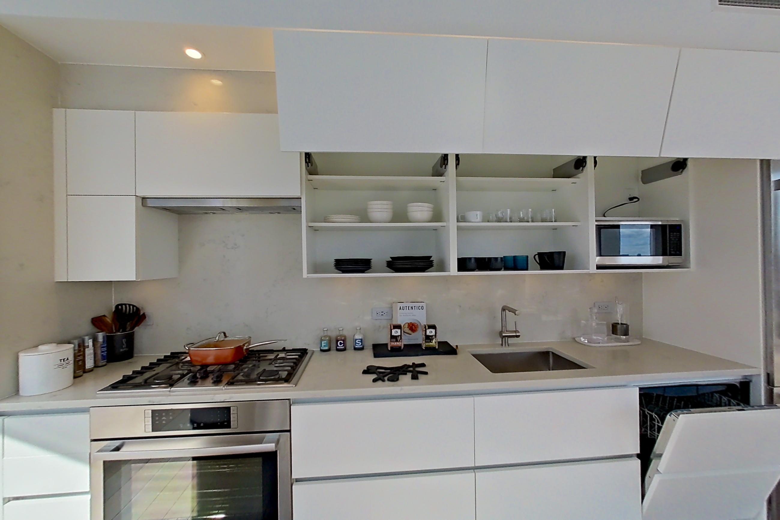 Kitchen with cooktop, dark wood-finish flooring, gas cooktop, light countertops, oven/range, stainless steel appliances, and wood-finish flooring, Apartment 28E at Summit NYC