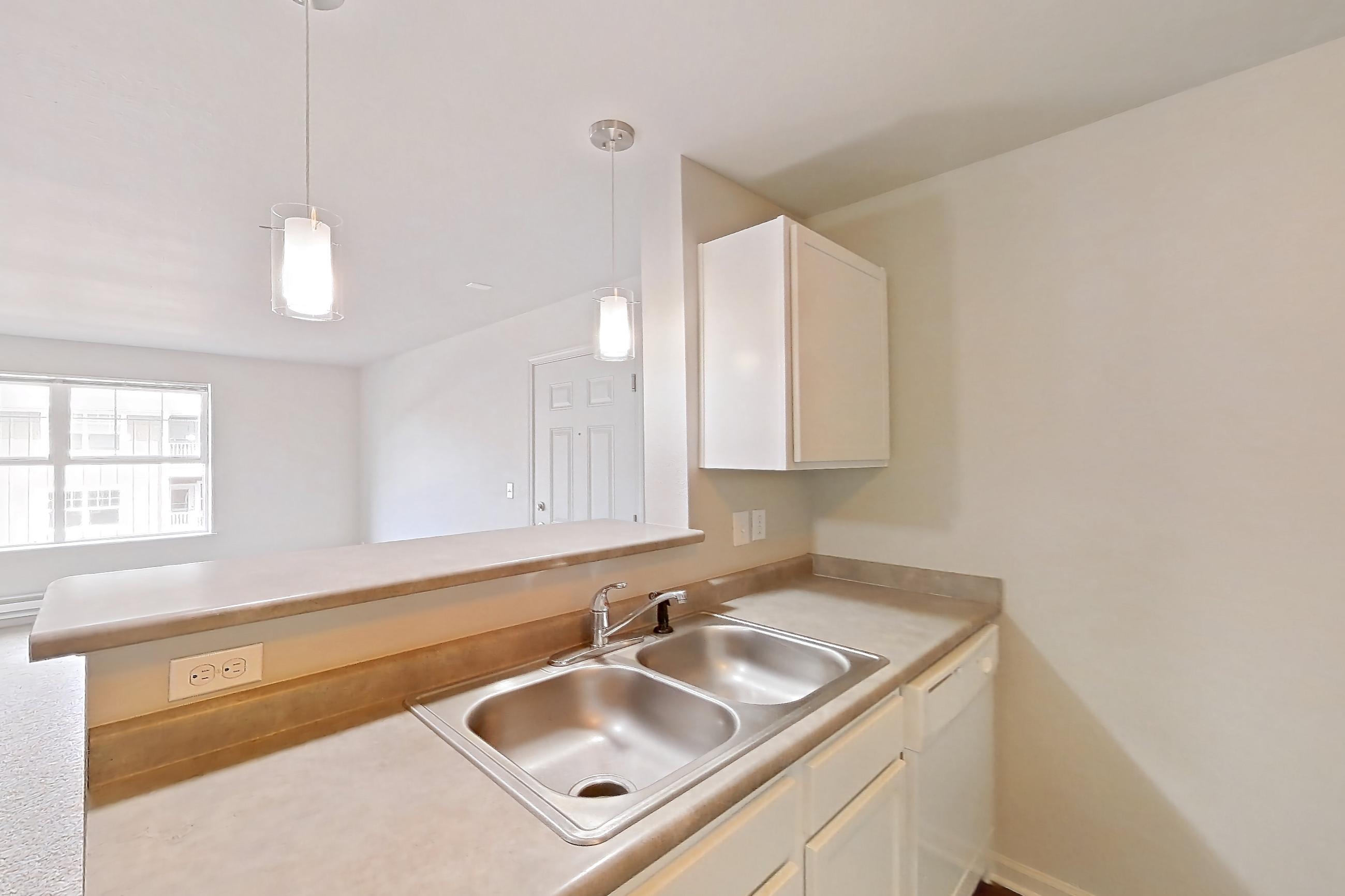 Kitchen with dark wood-finish flooring, dishwasher, electric range, light countertops, oven/range, range hood, refrigerator, and white appliances, Apartment 522 at Sunset View