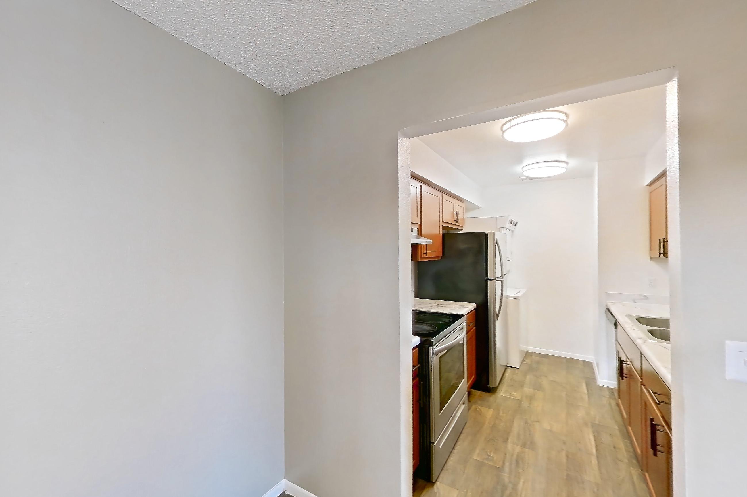 Dining room with dark wood-finish flooring, electric range, light countertops, oven/range, refrigerator, stainless steel appliances, and white appliances, Apartment 4060 Unit 10 at Aaron Lake Apartments