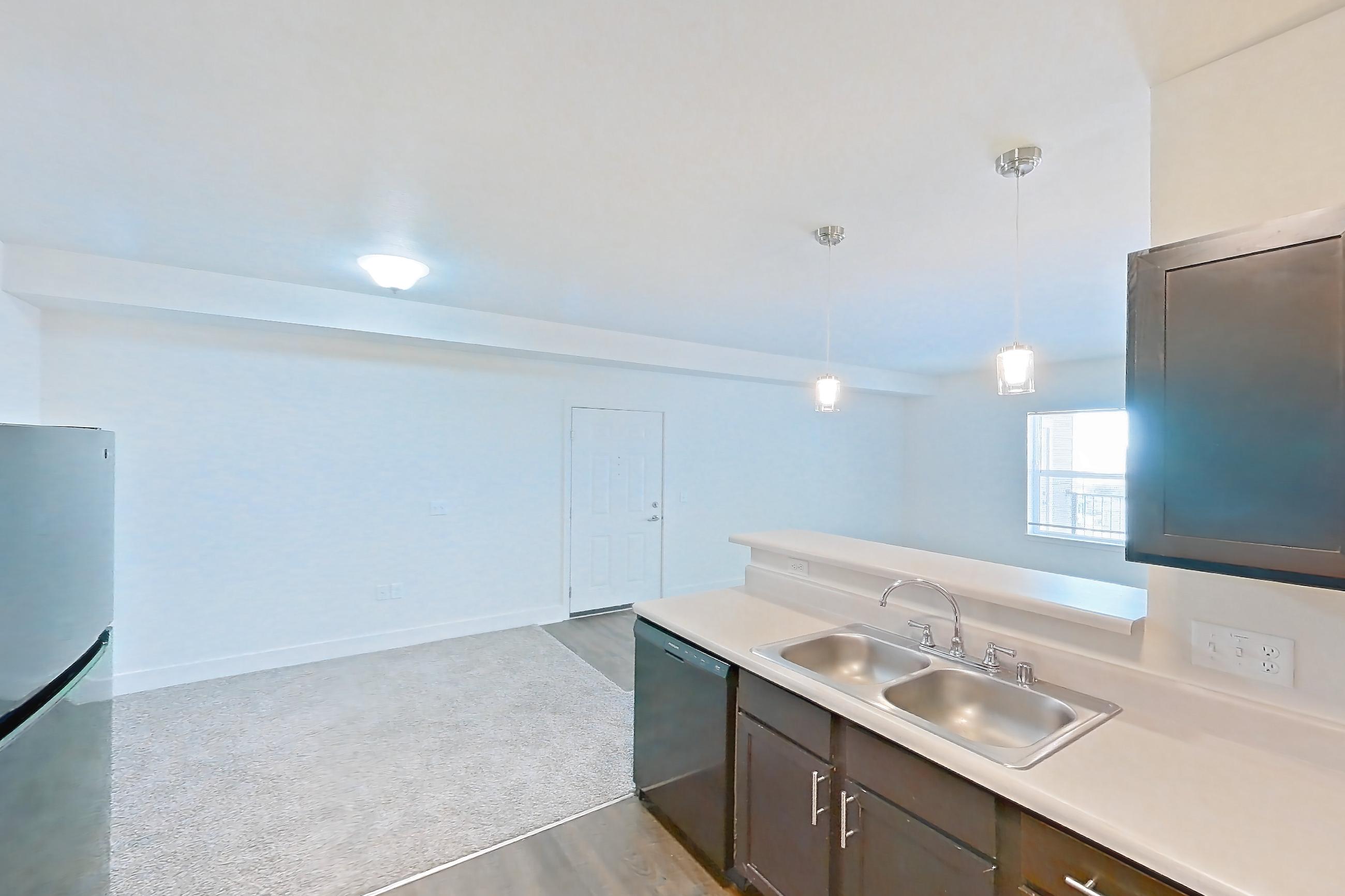 Kitchen with black appliances, dark wood-finish flooring, dishwasher, electric range, light countertops, light wood-finish flooring, oven/range, range hood, and refrigerator, Apartment 8304 at Larkridge