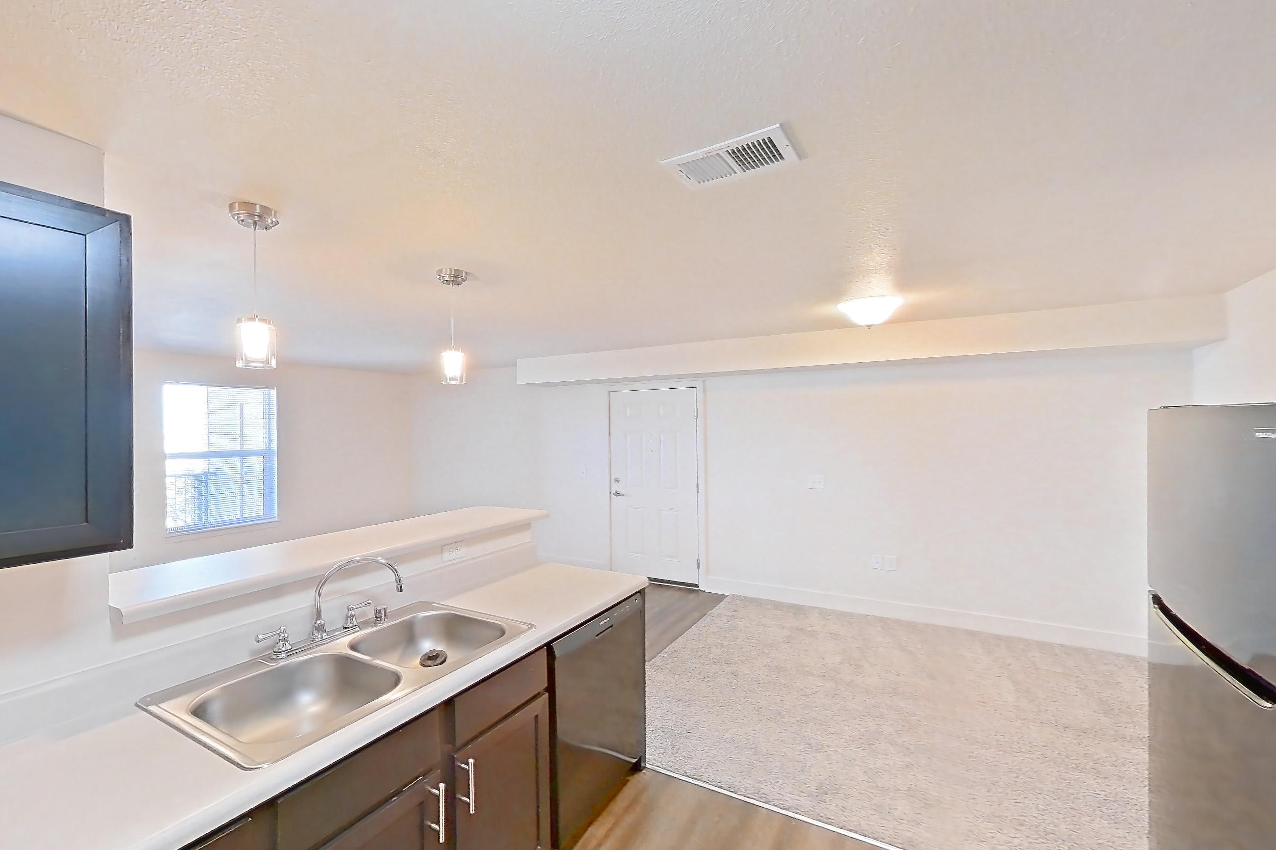 Kitchen with black appliances, dark wood-finish flooring, dishwasher, electric range, light countertops, oven/range, range hood, refrigerator, and stainless steel appliances, Apartment 4205 at Larkridge