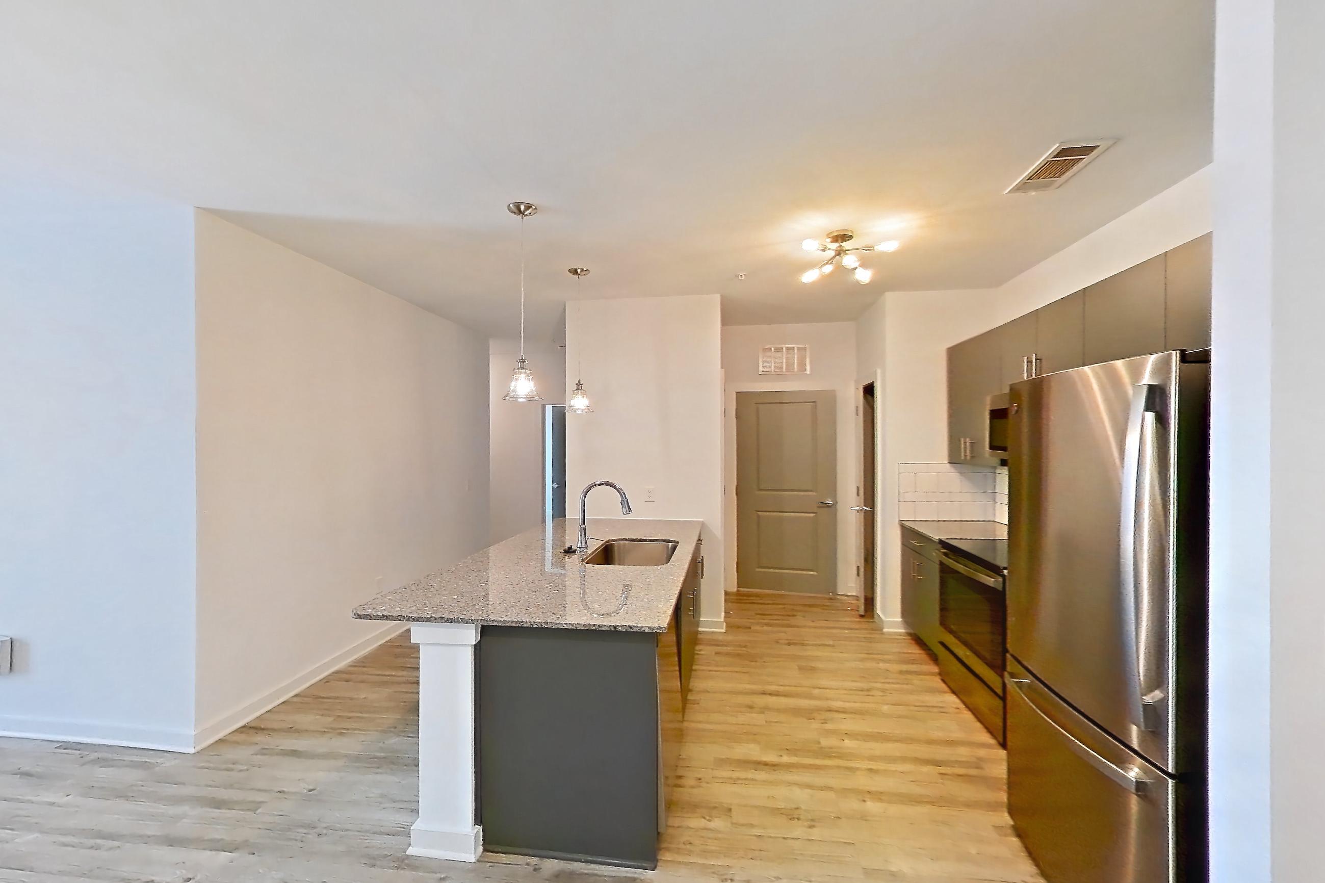 Dining room with electric range, light stone countertops, light wood-finish flooring, oven/range, refrigerator, and stainless steel appliances, Apartment 1211-105 at Avril Cambridge Village