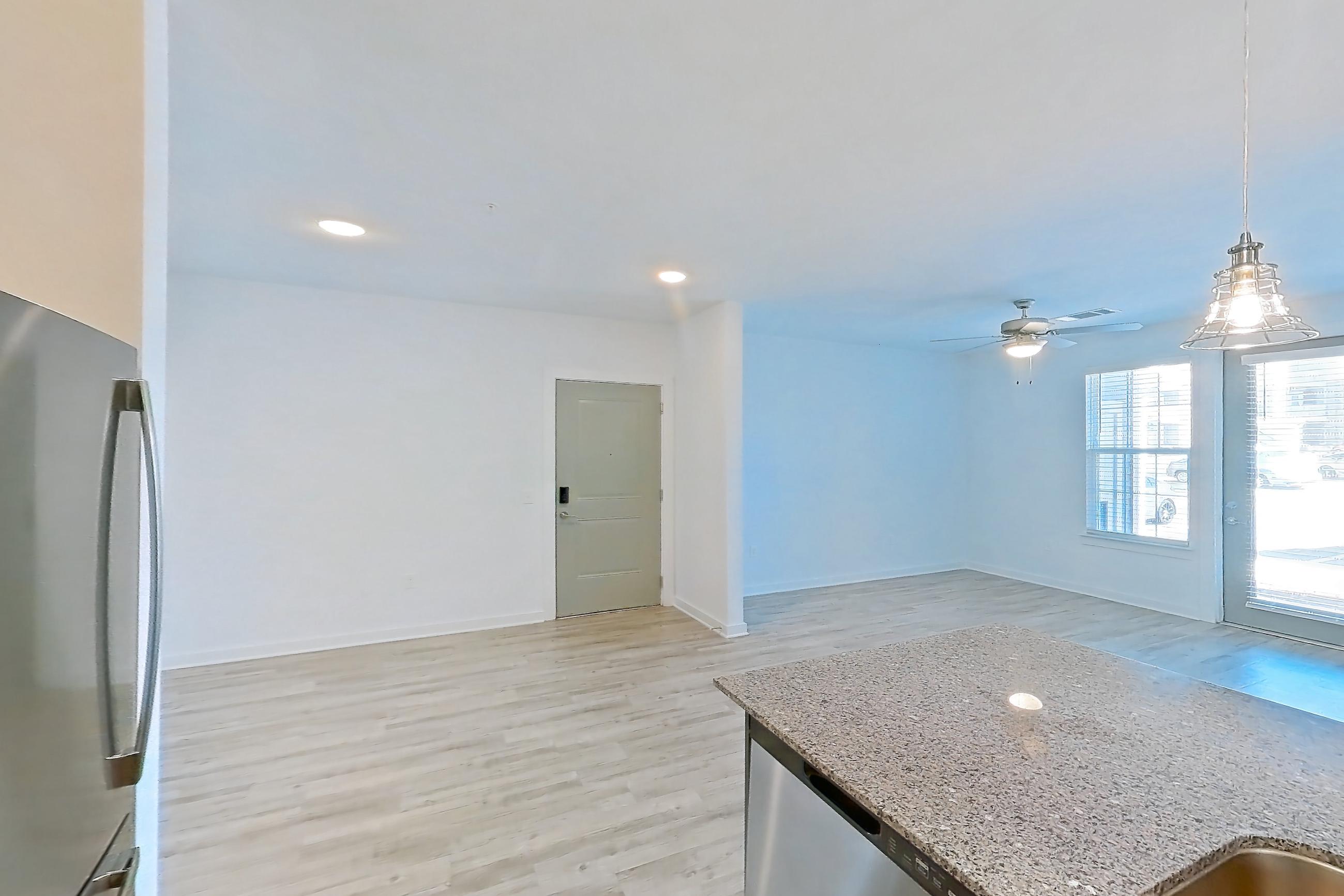 Kitchen with dark stone countertops, dishwasher, electric range, light stone countertops, light wood-finish flooring, microwave, oven/range, refrigerator, and stainless steel appliances, Apartment 1211-105 at Avril Cambridge Village