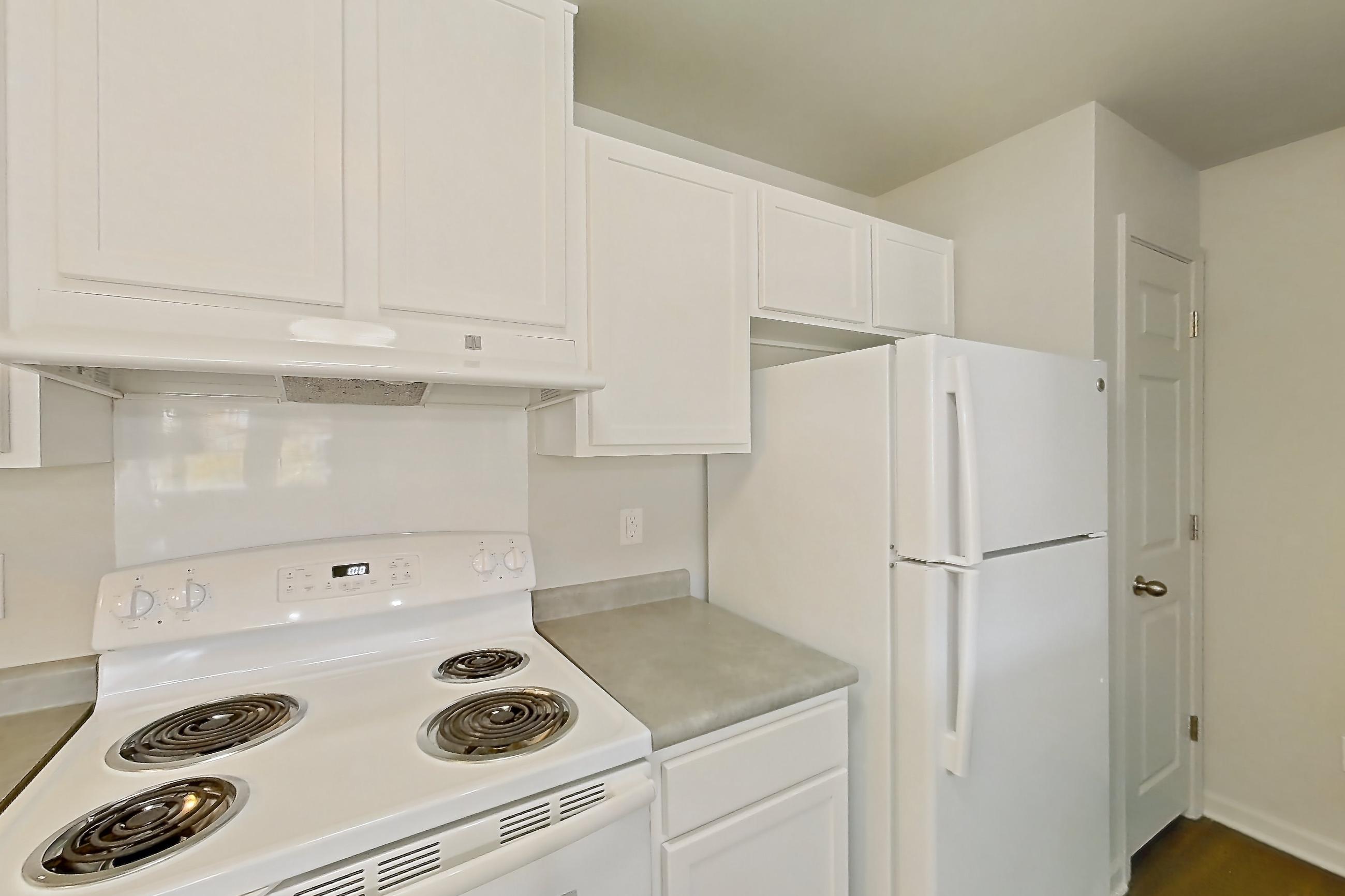 Kitchen with dark wood-finish flooring, dishwasher, electric range, light countertops, oven/range, refrigerator, and white appliances, Apartment 714 at Sunset View
