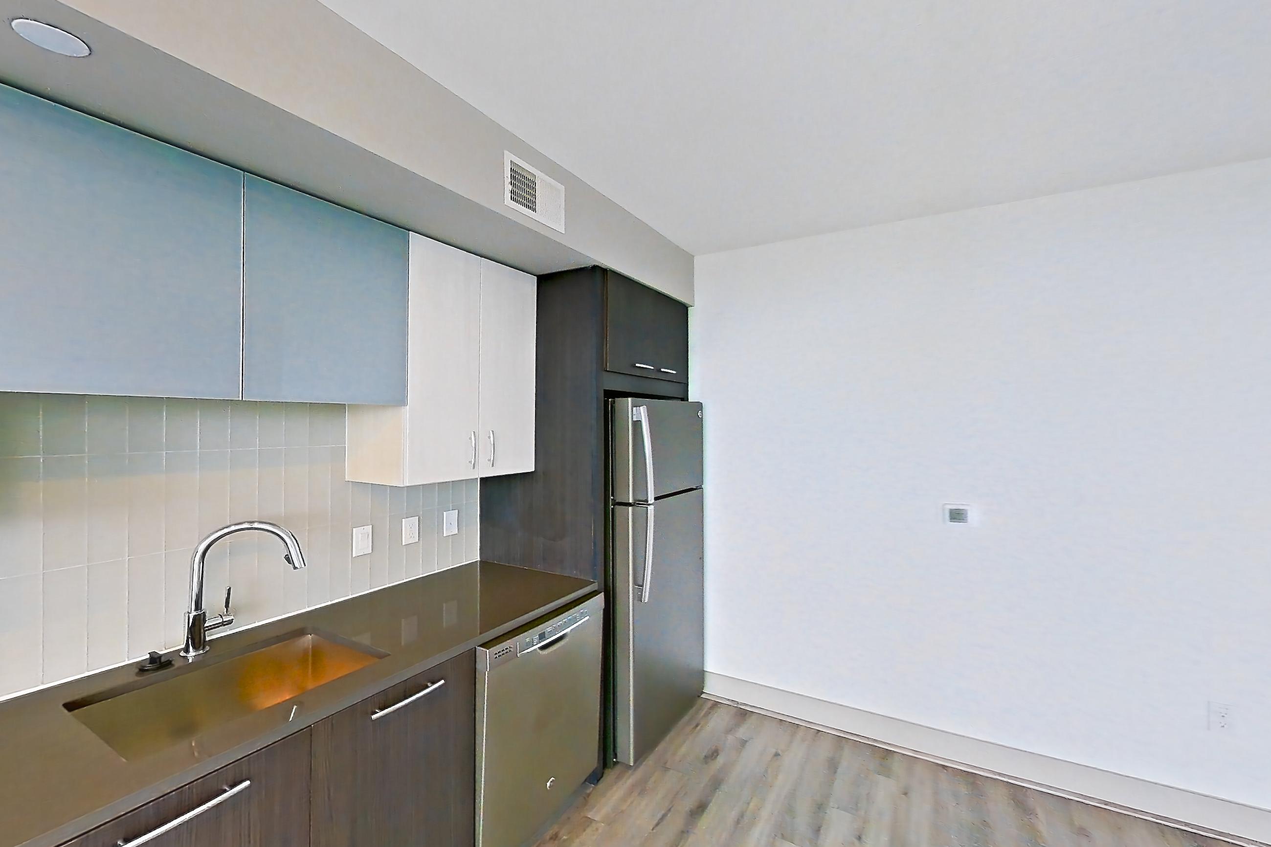 Kitchen with dark countertops, dishwasher, electric range, light wood-finish flooring, microwave, oven/range, refrigerator, and stainless steel appliances, Apartment 1811 at Adaire