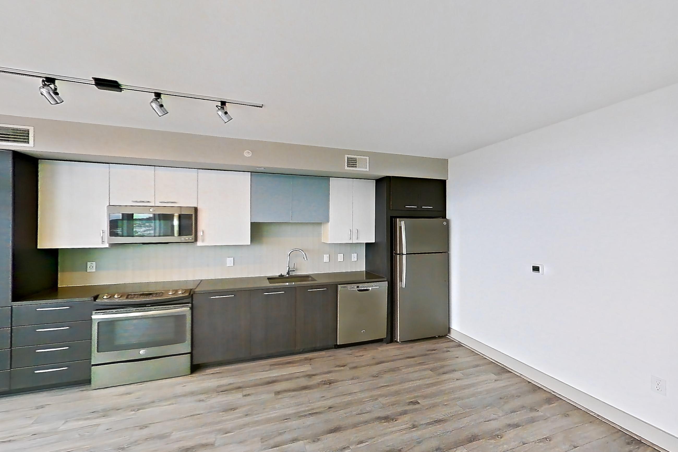 Living room with dark countertops, dishwasher, electric range, light wood-finish flooring, oven/range, refrigerator, and stainless steel appliances, Apartment 1811 at Adaire