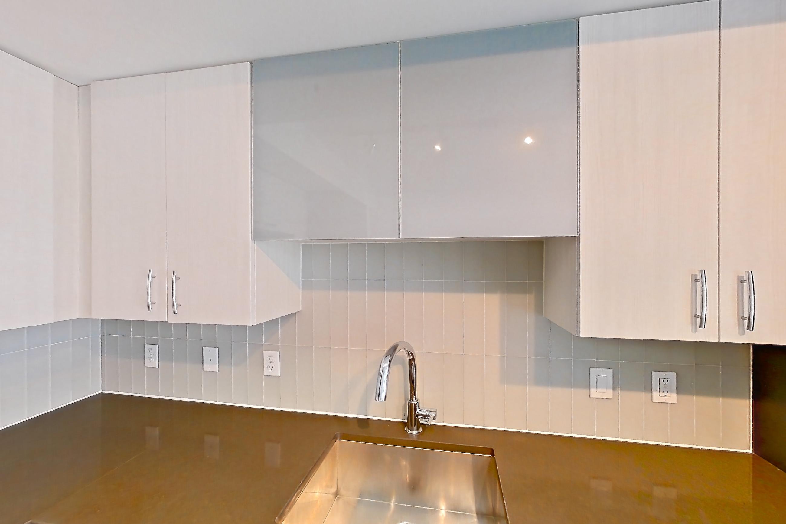 Kitchen with dark countertops, dark stone countertops, dishwasher, electric range, light countertops, light wood-finish flooring, microwave, oven/range, refrigerator, stainless steel appliances, and white appliances, Apartment 906 at Adaire