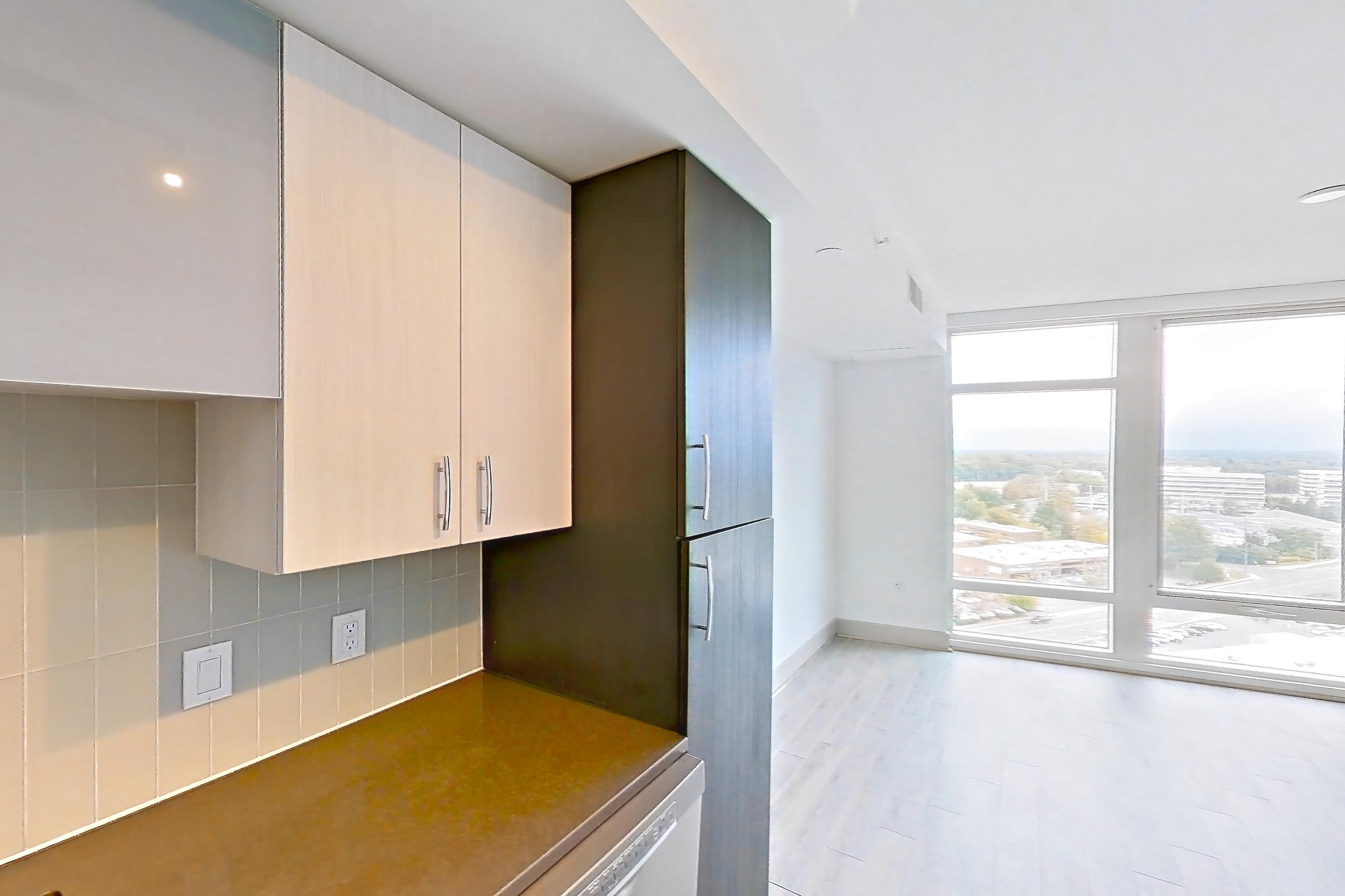 Kitchen with dark countertops, dark stone countertops, dishwasher, electric range, light wood-finish flooring, microwave, oven/range, refrigerator, stainless steel appliances, and white appliances, Apartment 1606 at Adaire