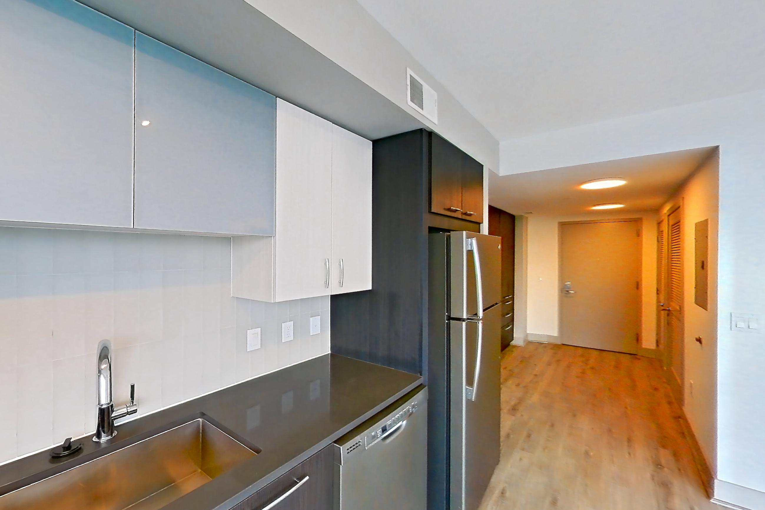 Kitchen with dark countertops, dishwasher, electric range, light countertops, light wood-finish flooring, microwave, oven/range, refrigerator, and stainless steel appliances, Apartment 902 at Adaire